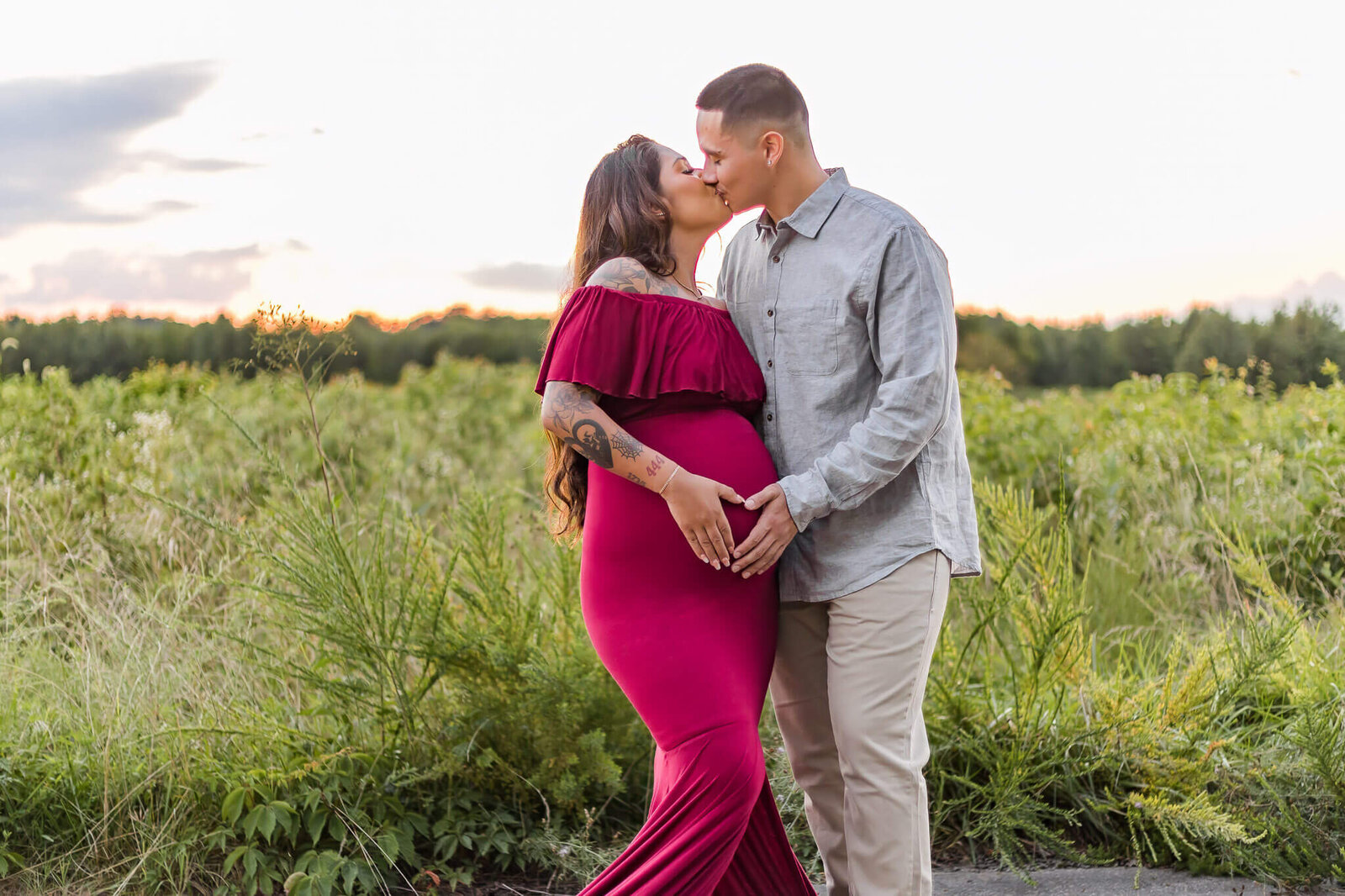 A couple expecting their first baby kissing and holding mom's belly.