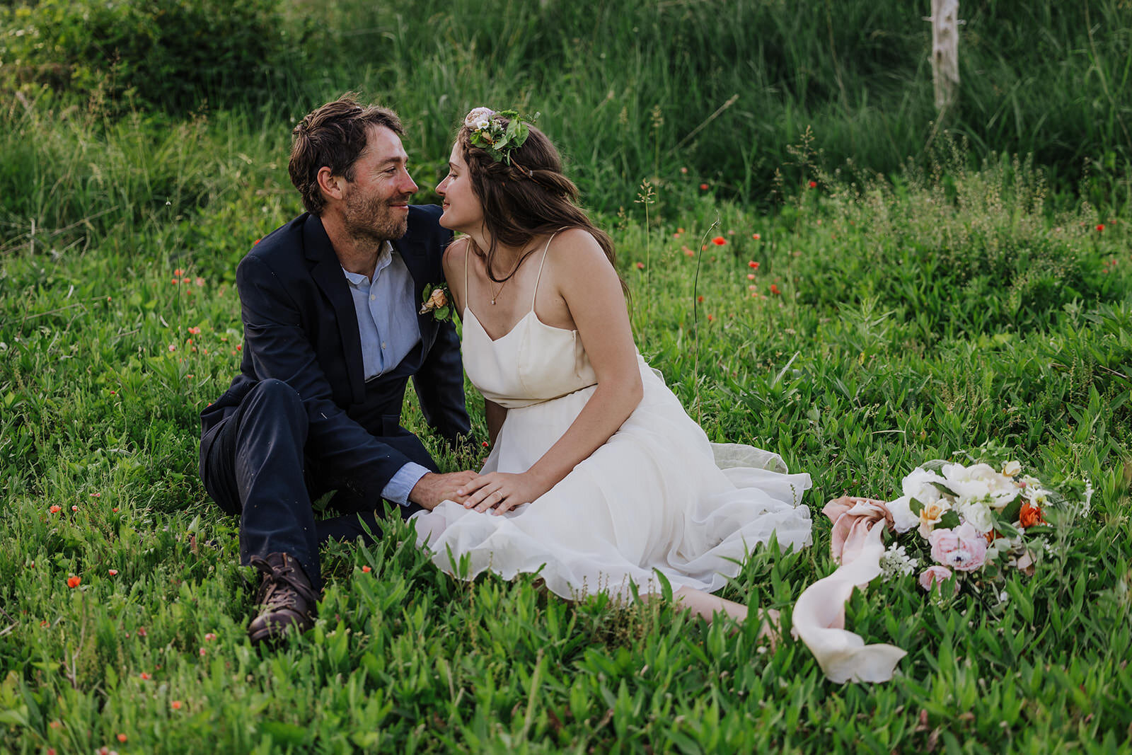 A couple sits in a filed of wildflowers on their elopement day 