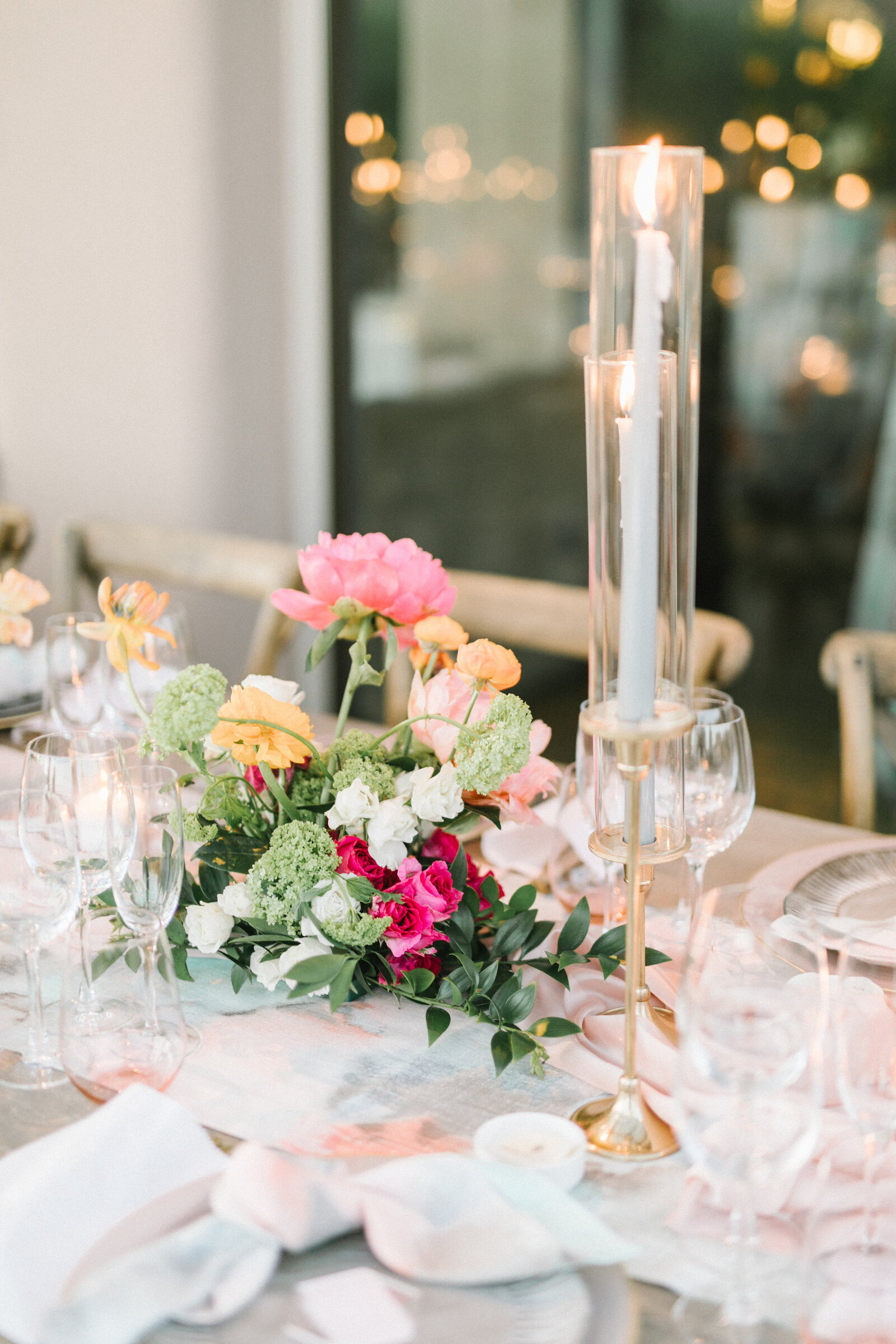 Wedding reception table decorated with colorful flowers and candles.