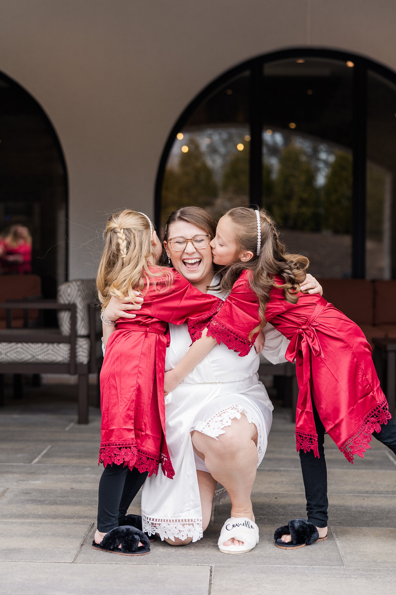 Bride hugging her flower girls in matching robes during wedding morning prep at Perona Farms in New Jersey.