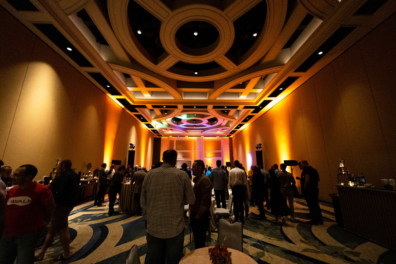 Guests mingling in a ballroom with dramatic ceiling and warm lighting