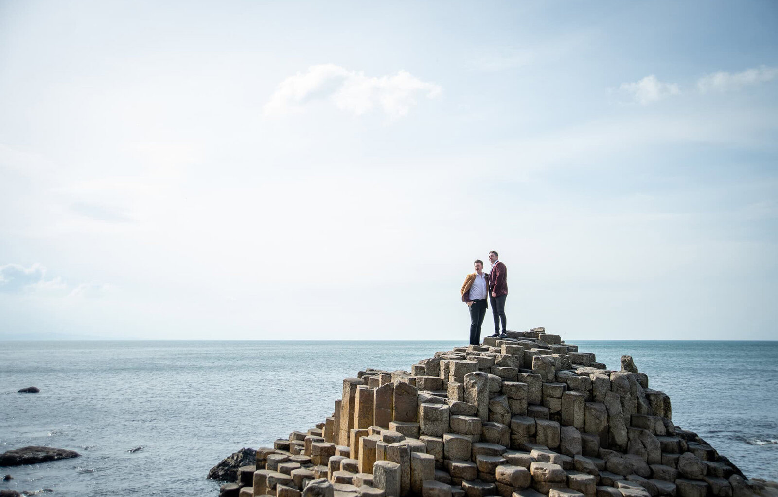 two grooms standing on stone formation