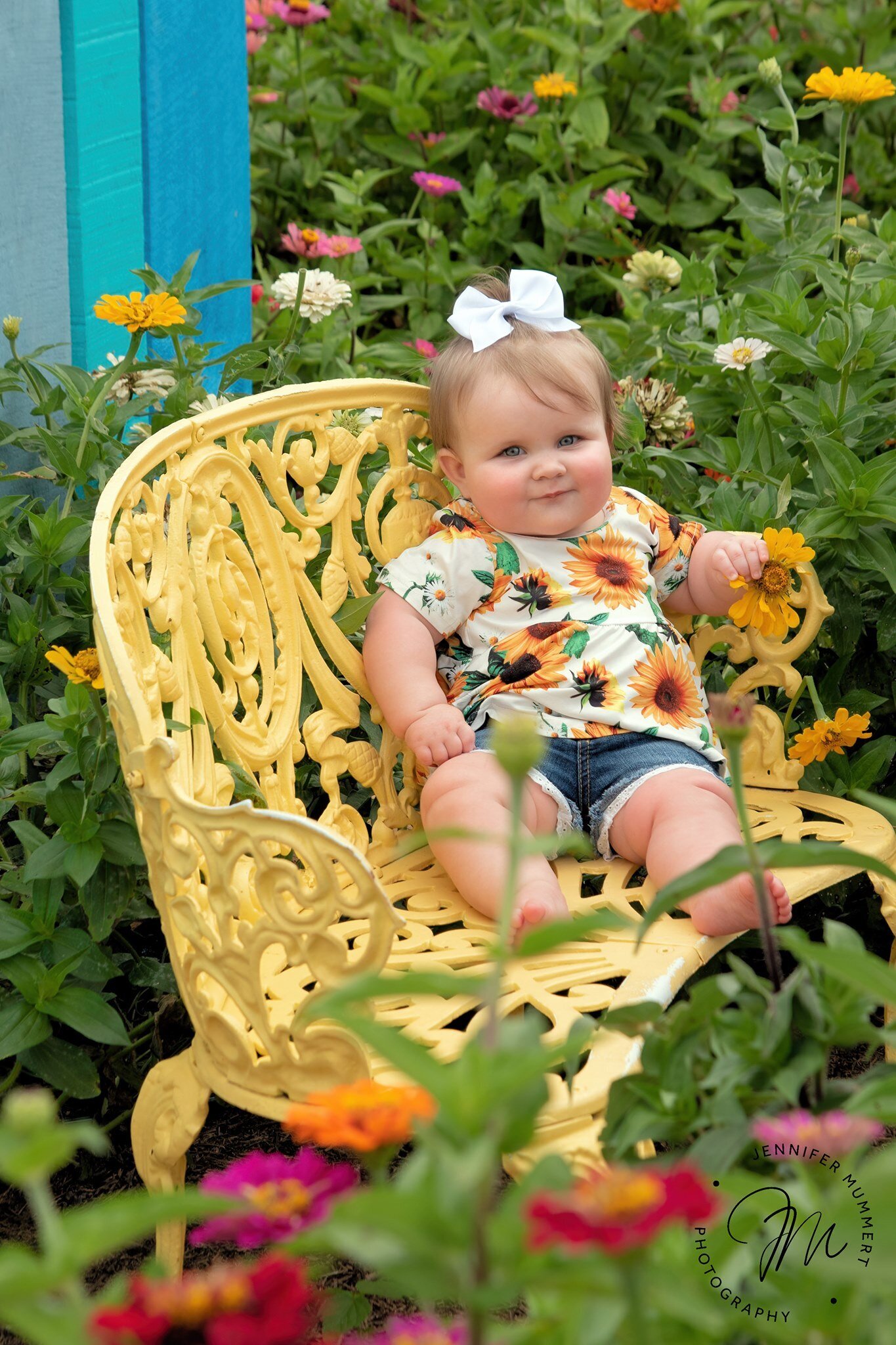 Baby in yellow chair sitting in flowers