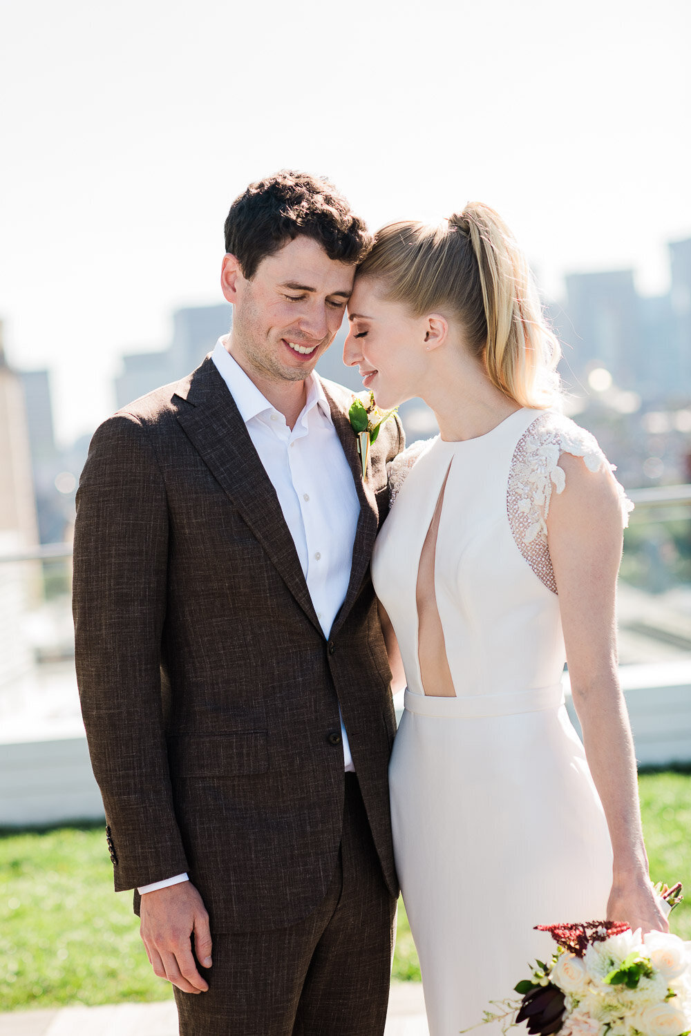 bride and groom foreheads together on Boston rooftop