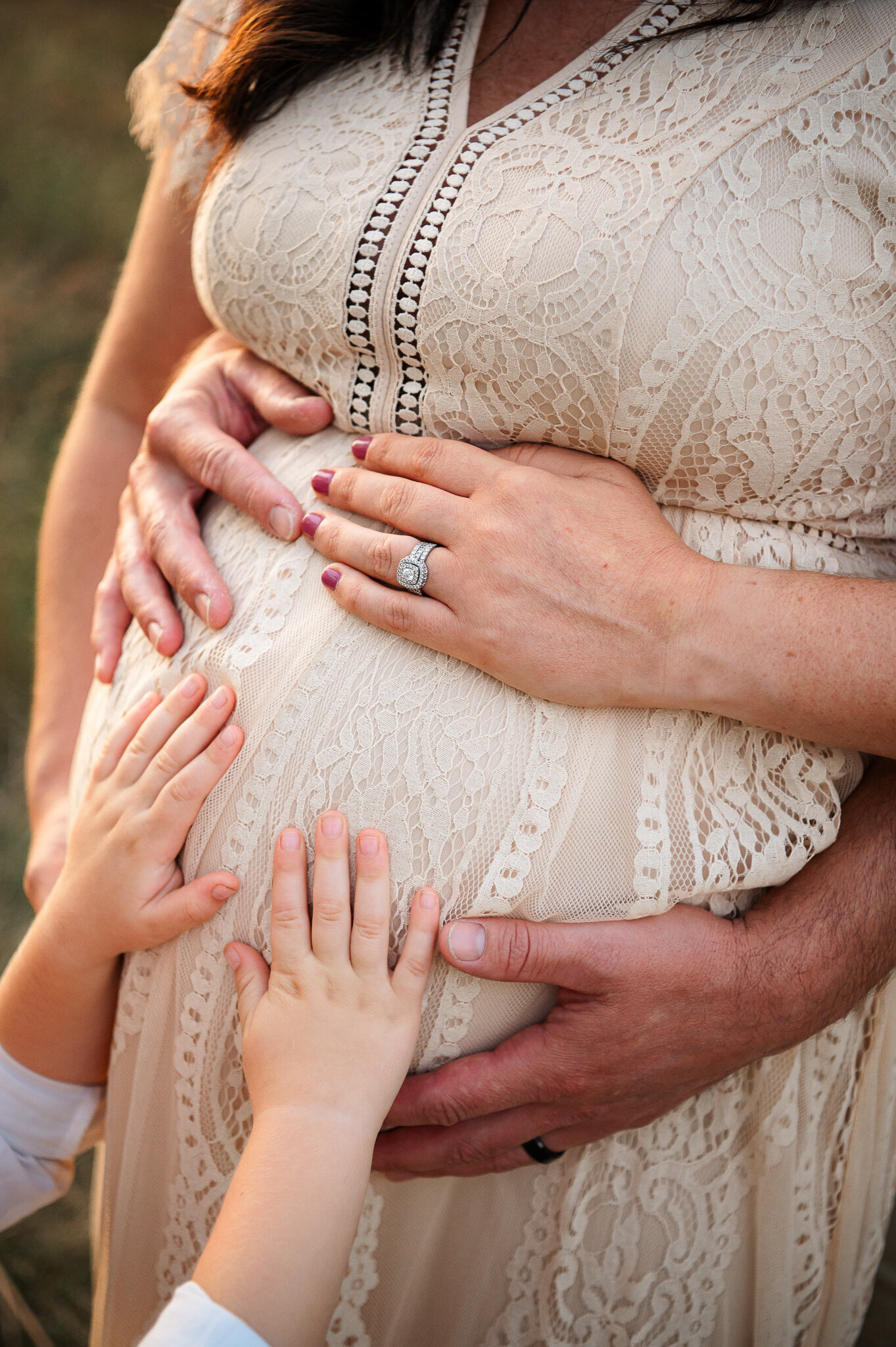 Detail natural light maternity session family holding mothers belly
