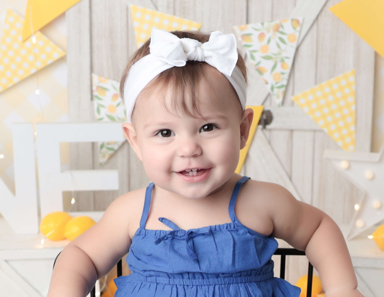 A sweet girl during her cake smash photography session in Rochester, NY. The scene captures her delighted expression, showcasing a fun and lively celebration.