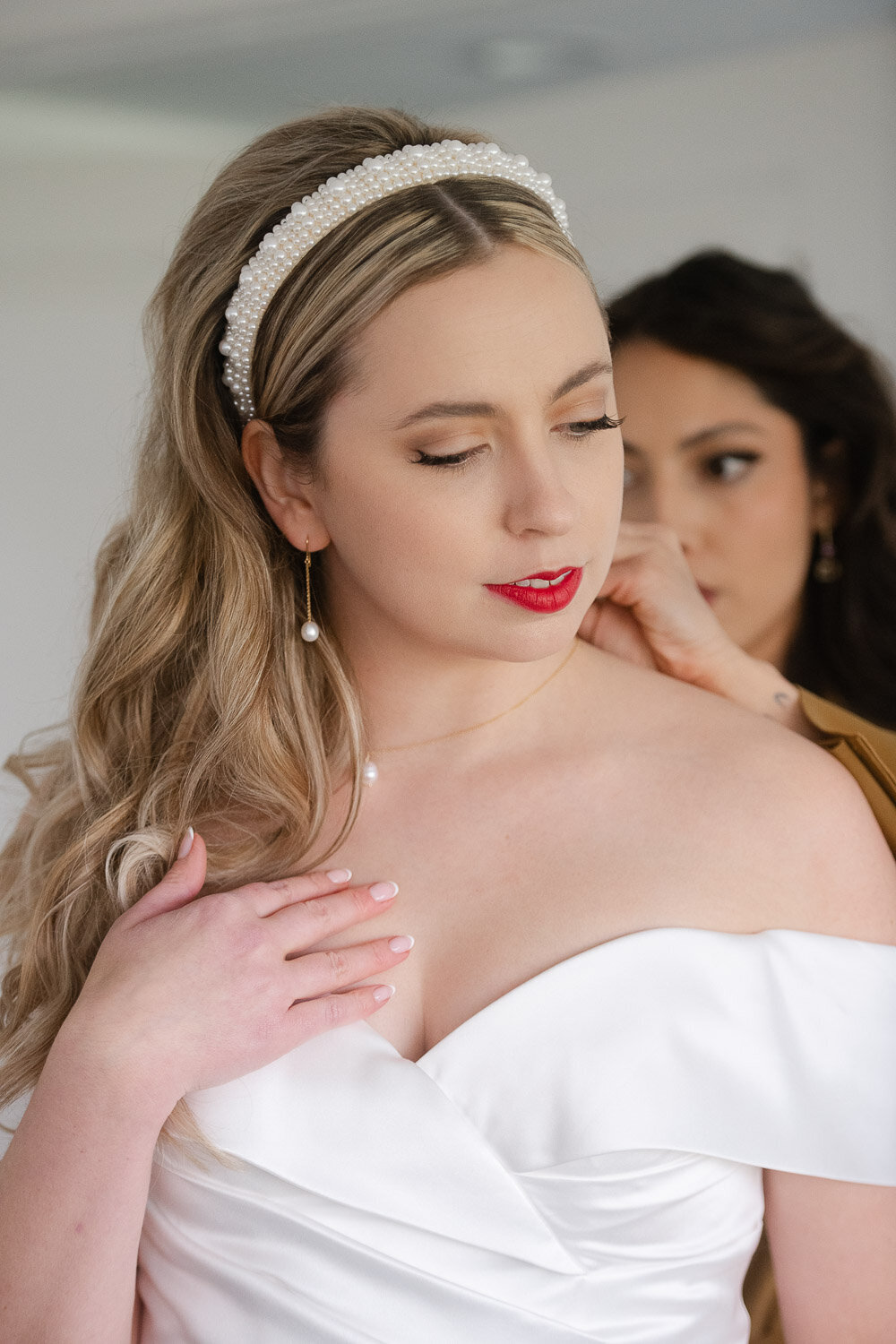 bridesmaid putiting necklace on bride