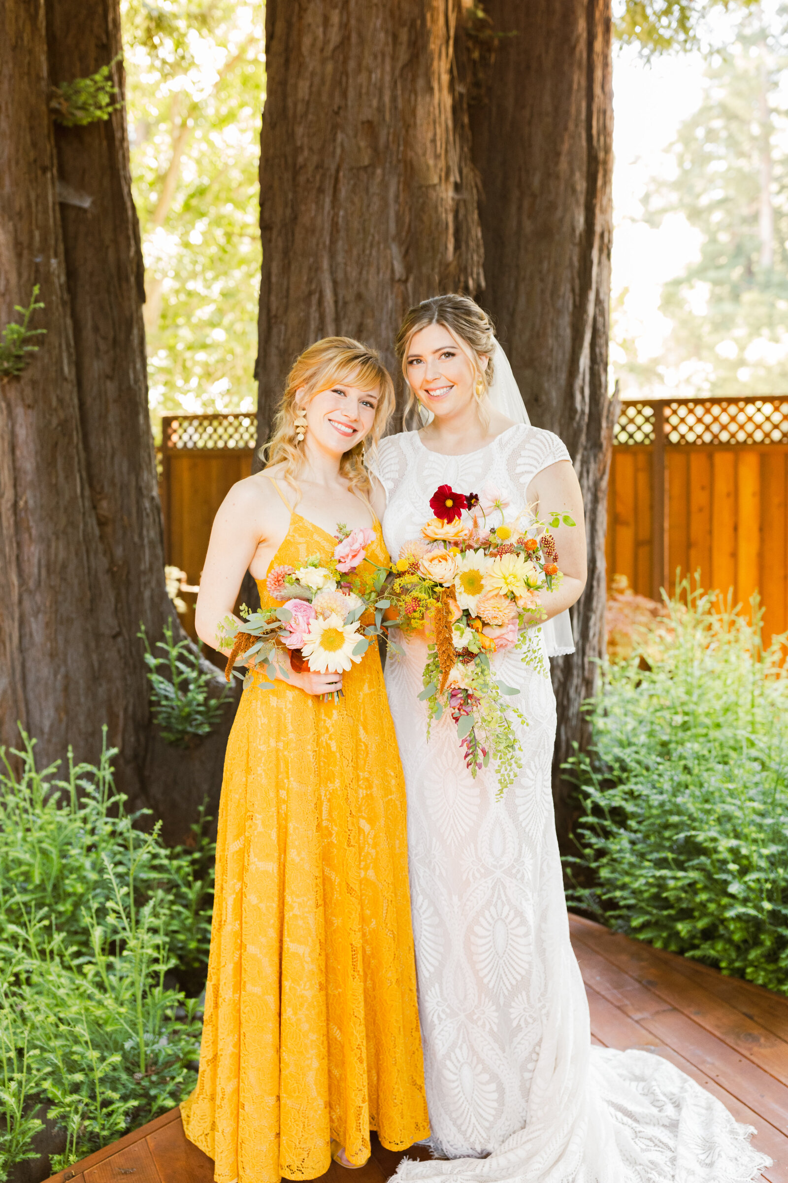 Bride and bridesmaid at her colorful wedding ceremony in Santa Cruz, California in the redwood trees.