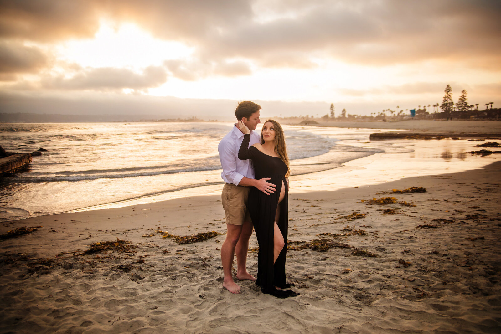 Maternity Photographer, a couple holds each other at the beach at sunset, she is pregnant