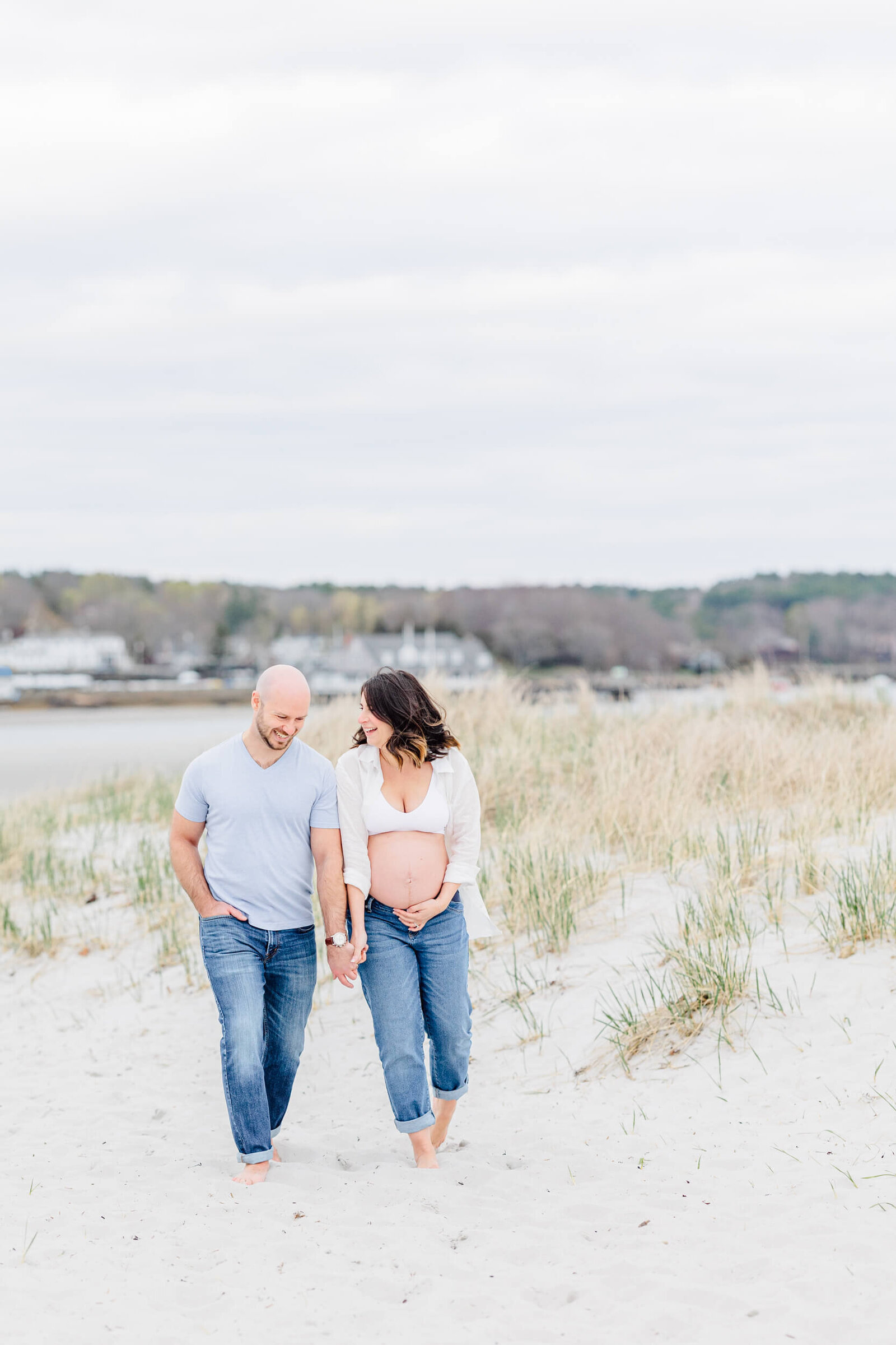 Pregnant woman and her husband laugh together on a sandy path