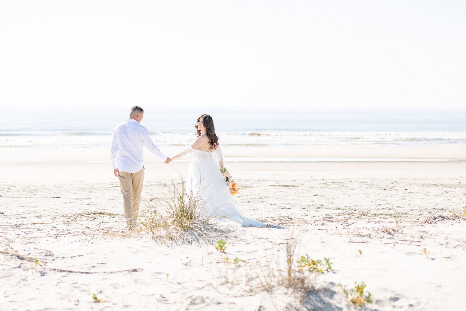bright light and airy wedding photo of bride and groom beach wedding ceremony