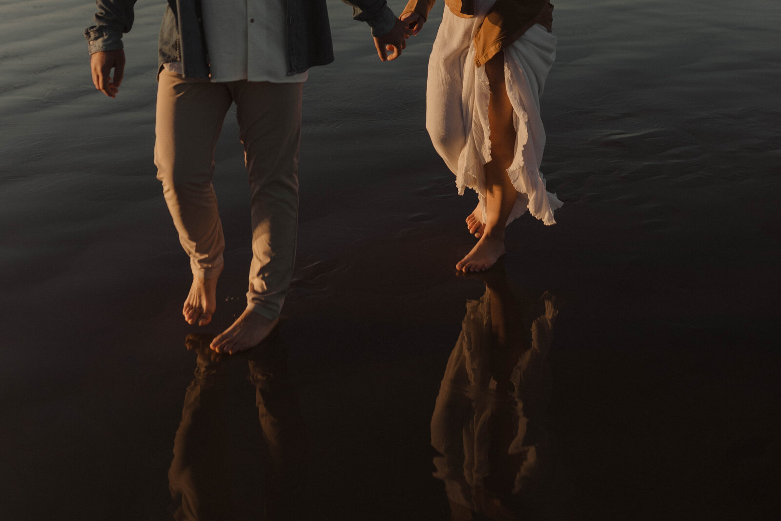 Couple barefoot walking through ocean