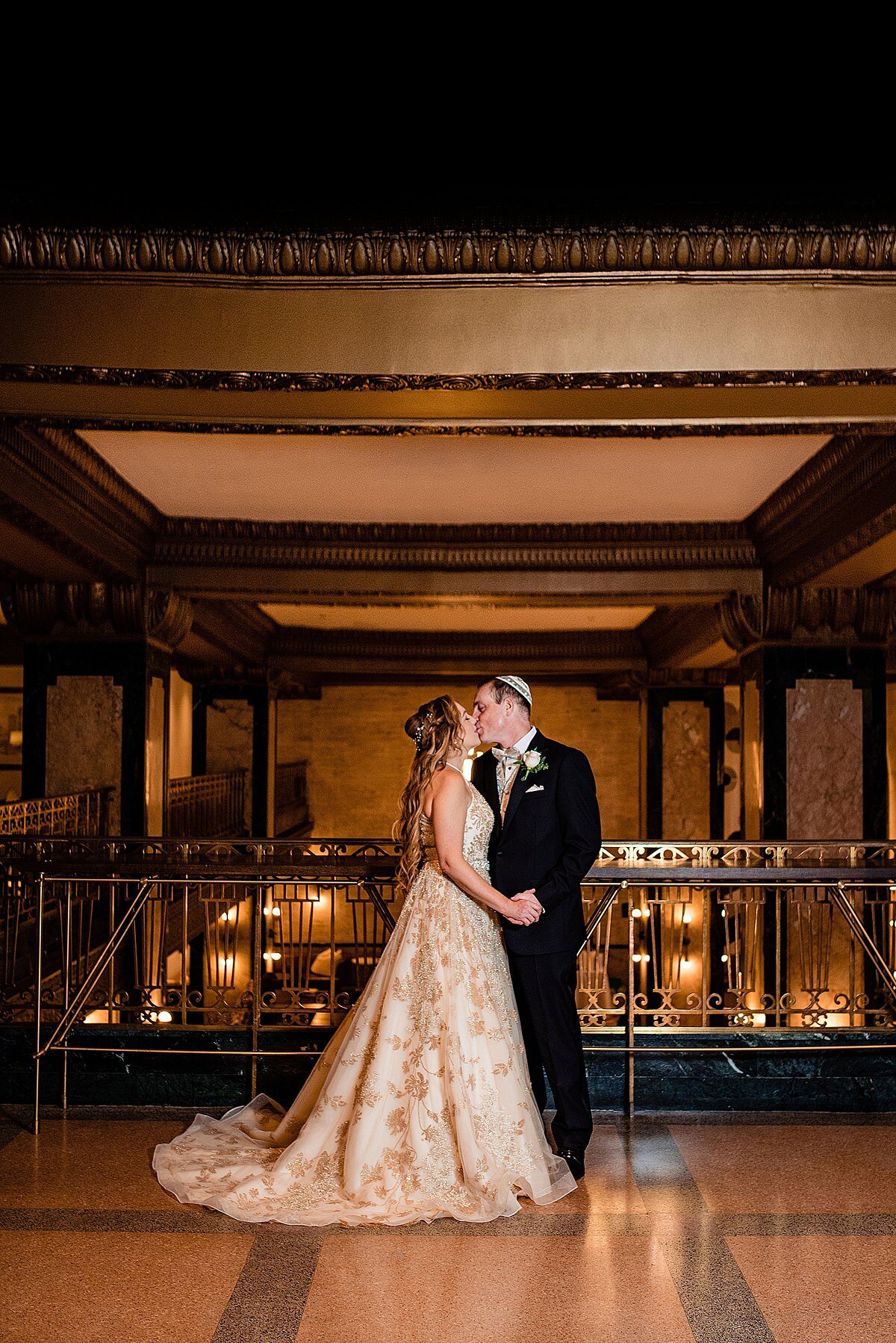 The bride in a gold and ivory dress kisses the groom in a dark blue suit at the mid century modern hotel, Noelle, in Nashville