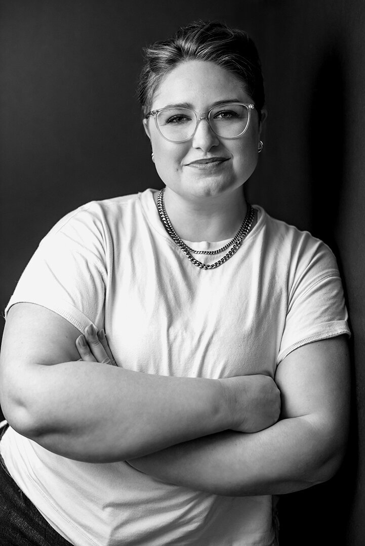 Black and white headshot of a  plus-size woman wearing a white t-shirt and glasses