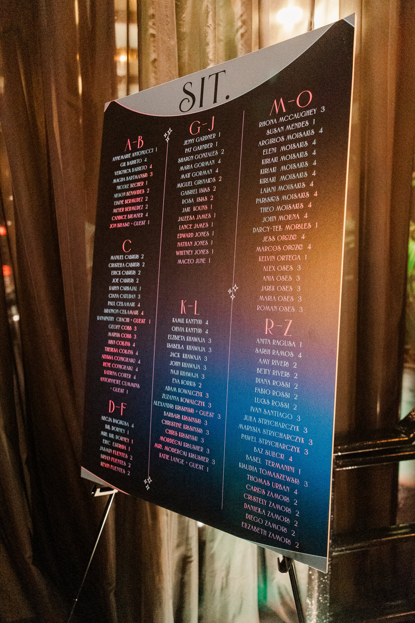 A black wedding seating chart with rainbow wedding guest names.