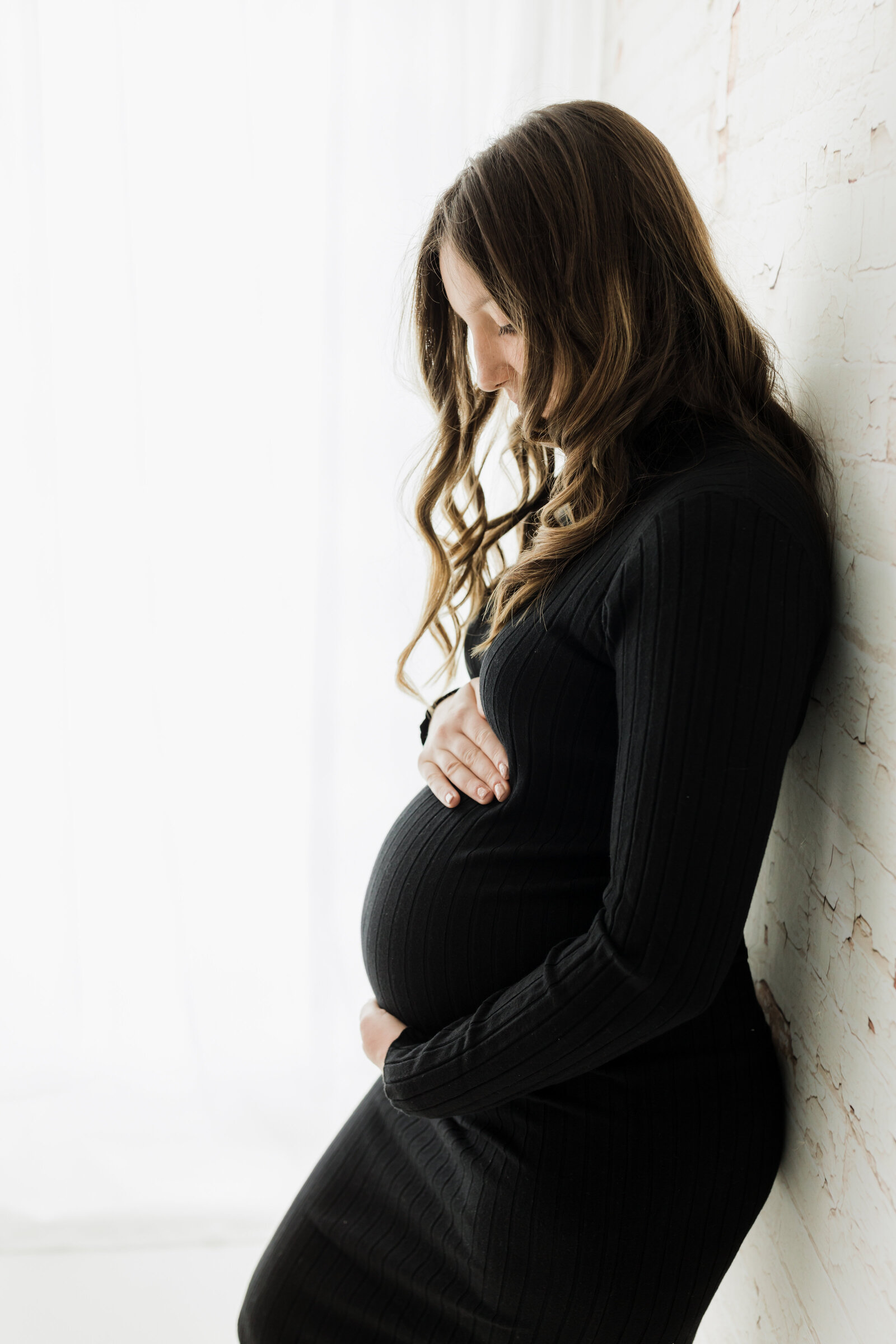 pregnant mother in black maternity dress holding baby bump for studio maternity photoshoot cleveland maternity photographer