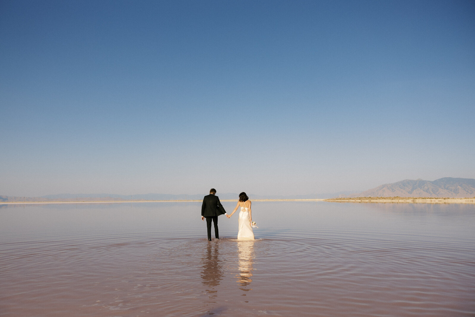 bride and groom walking together at pink lakes in utah