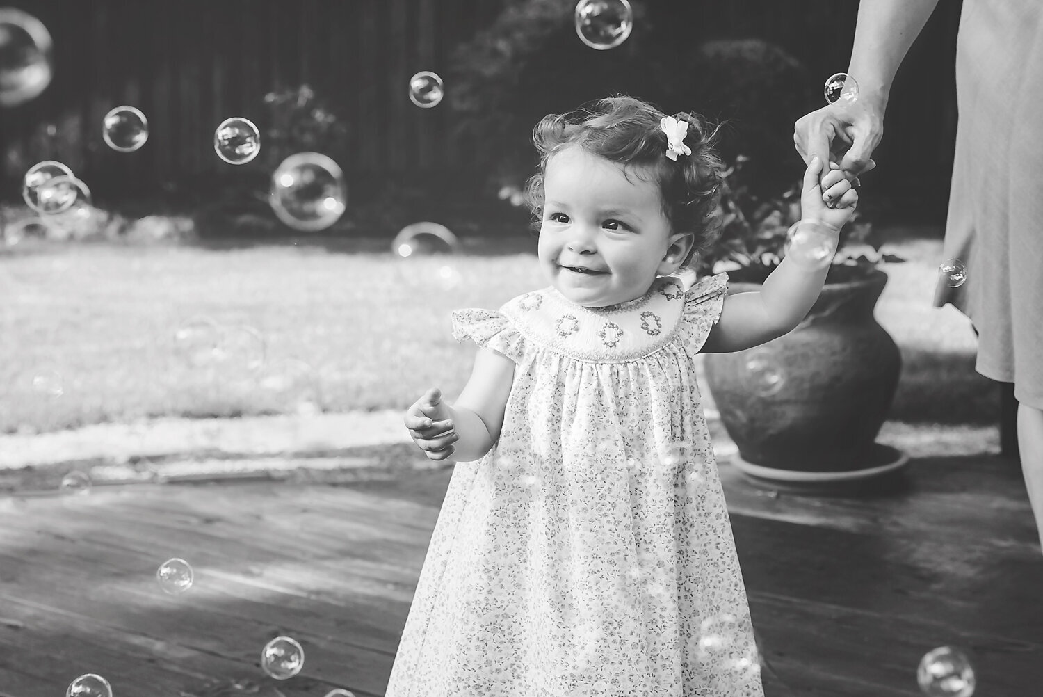 Black and white image of a young girl blowing bubbles at her one year milestone photo shoot in Dallas, TX