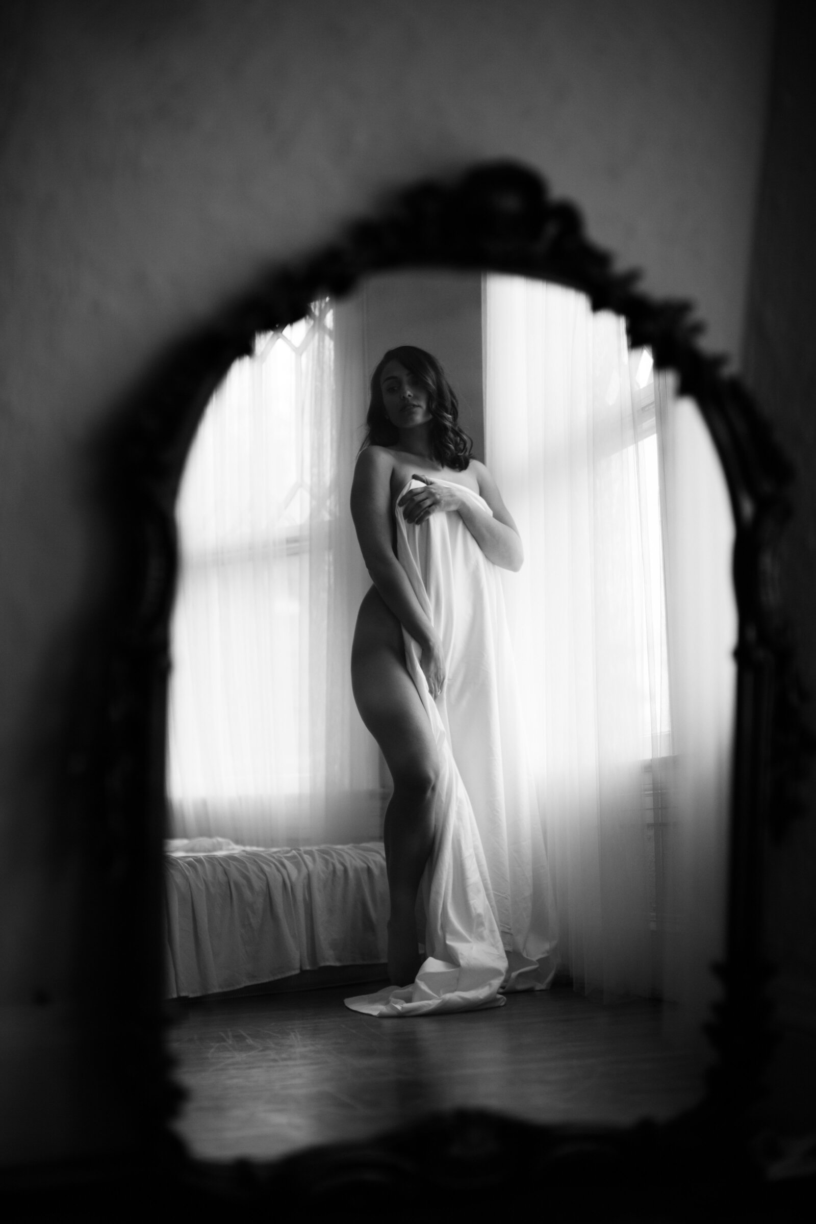 Black and white boudoir photo of woman wearing white dress