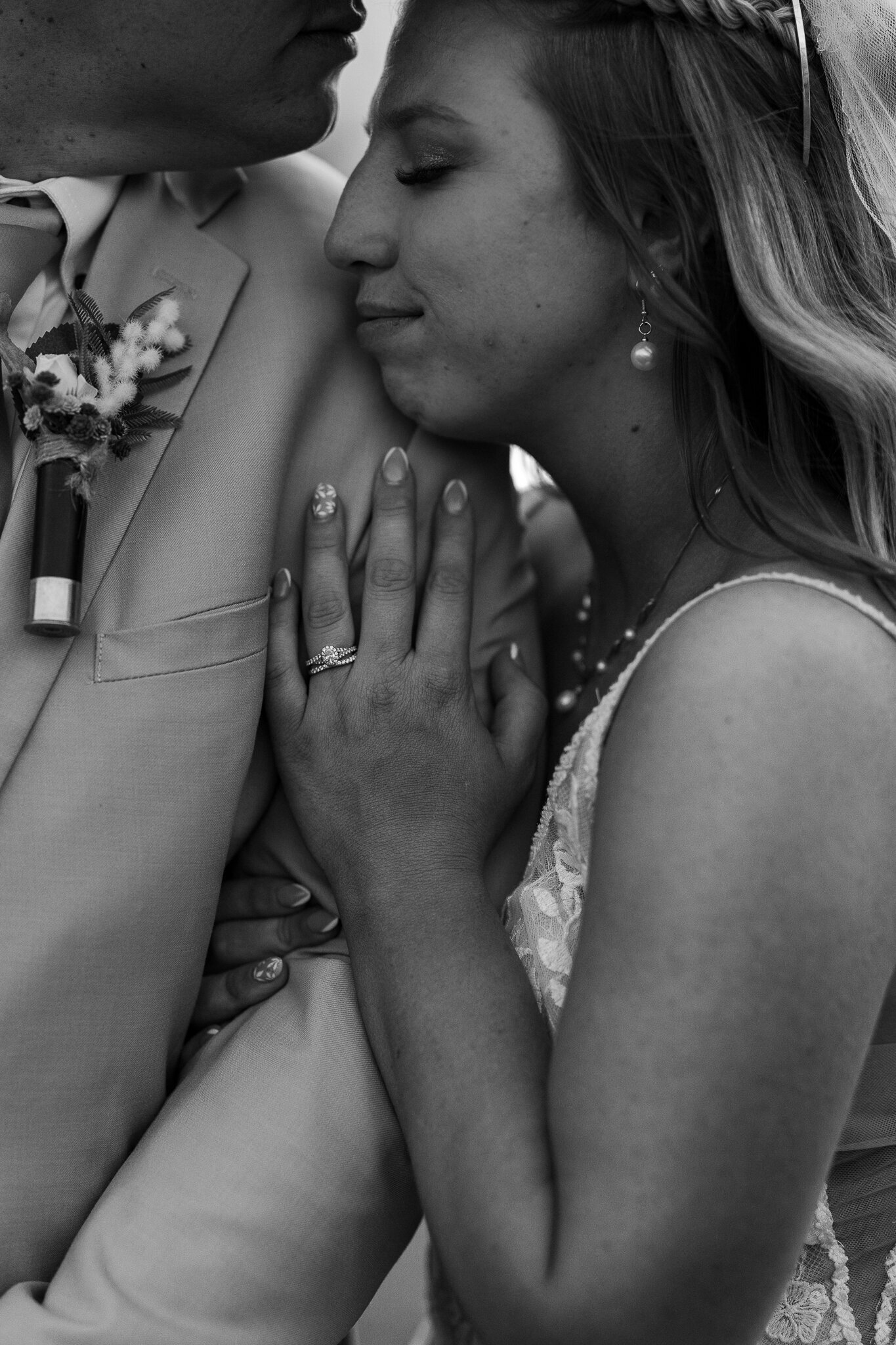 Close-up of the bride holding the groom’s elbow, her face softly smiling during portraits at their Loma wedding.
