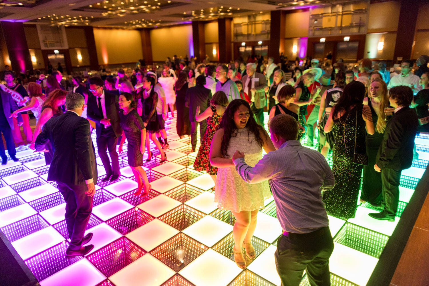 Crowd dancing on an illuminated checkered dance floor