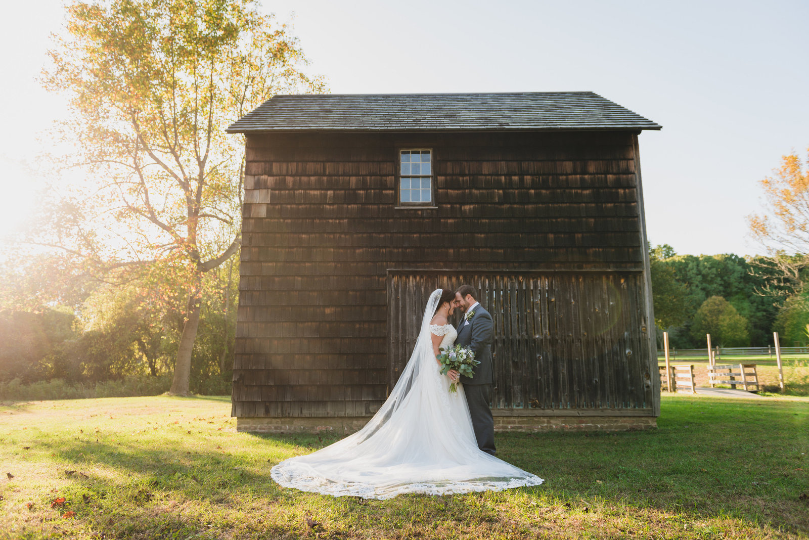 bride and groom posing in front of barn at The Barn at Old Bethpage