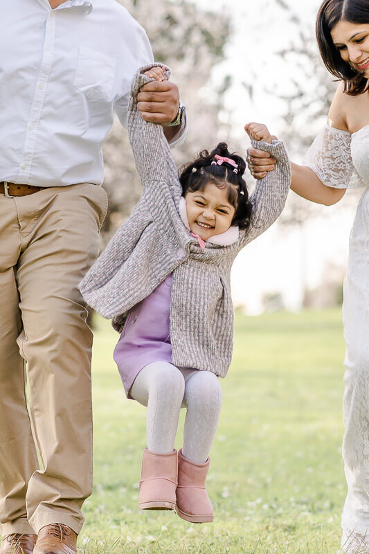 playful interactive shot of toddler in cherry blossoms during family pictures with hikari lifestyle photography