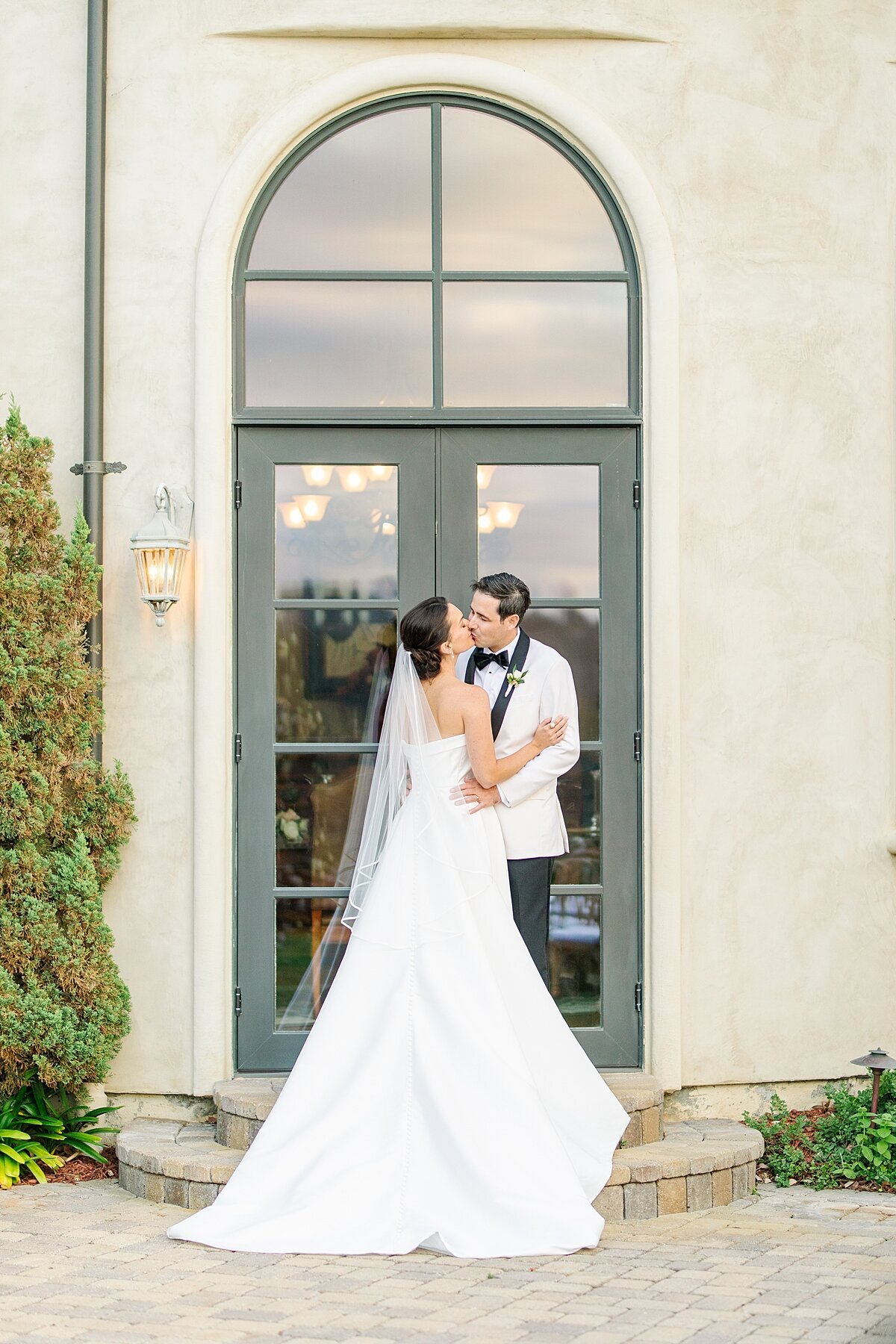 Bride and groom sneaking a kiss during their golden hour romantic portraits outside a private residence in Rancho Santa Fe, California.