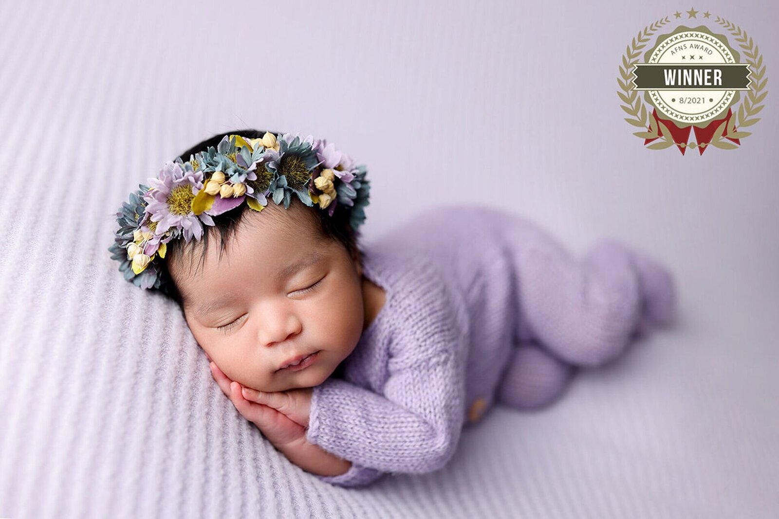 Newborn posing with a soft, pastel-colored background