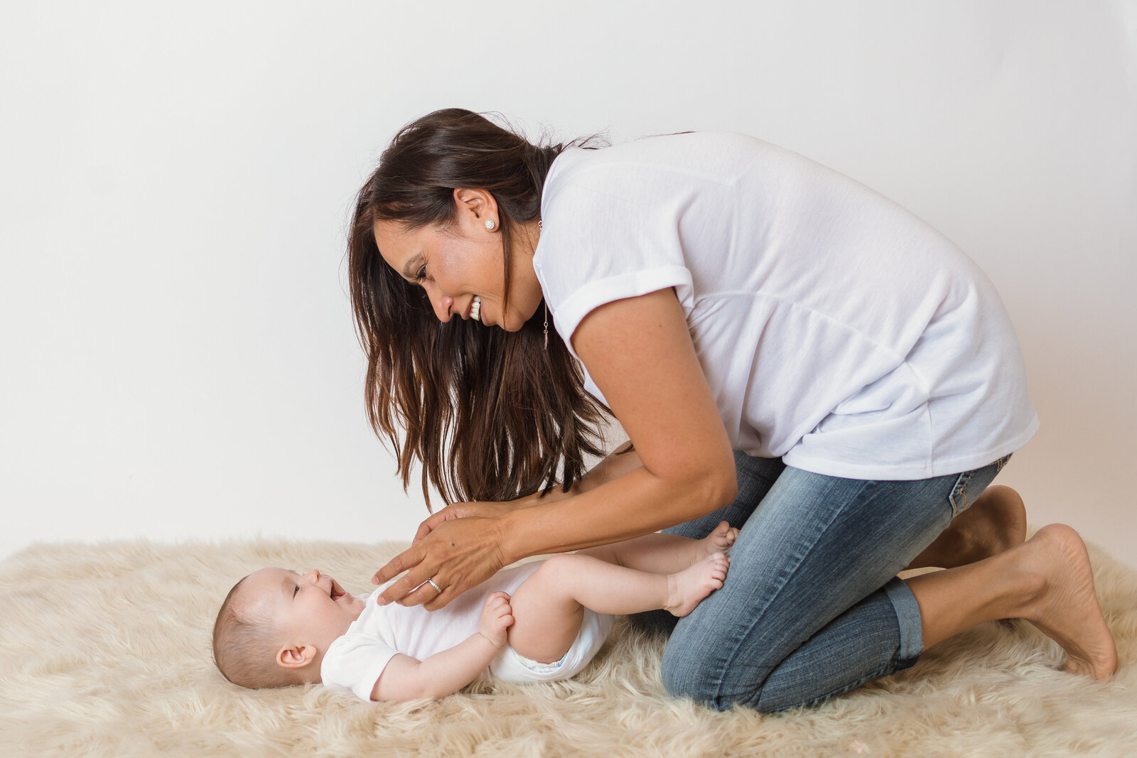 Milestone Photographer, baby lays on a rug as mom smiles and plays with him