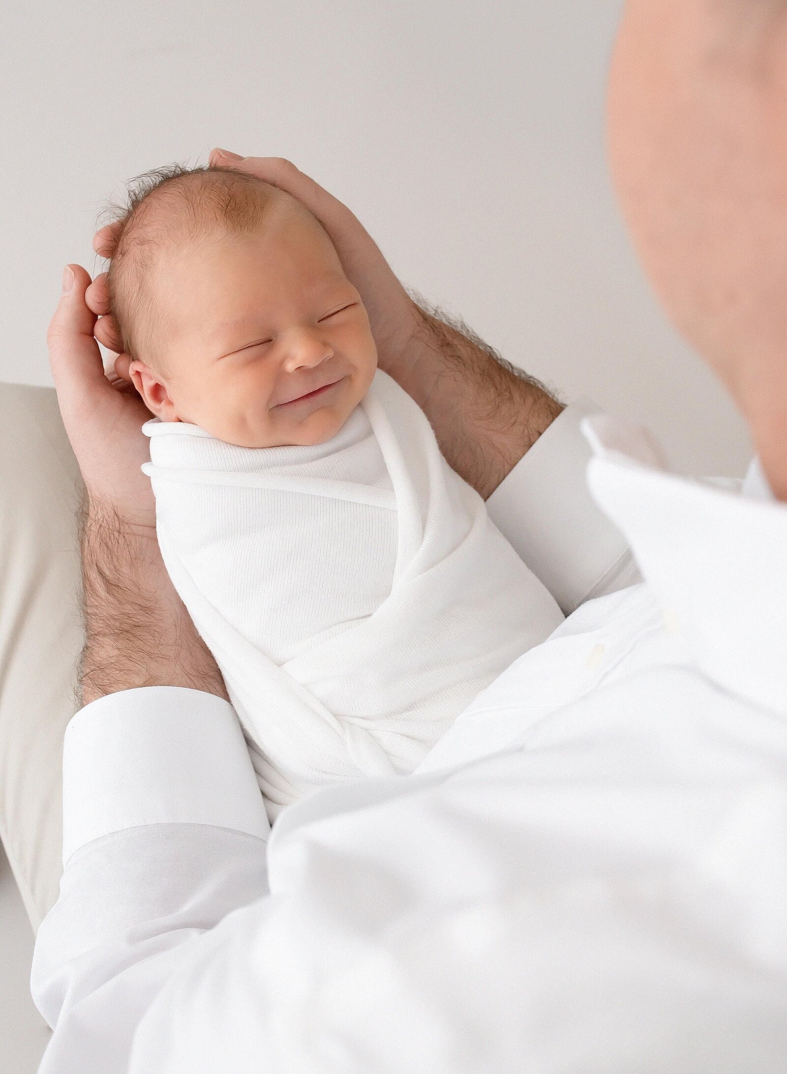 smiling newborn in fathers arm