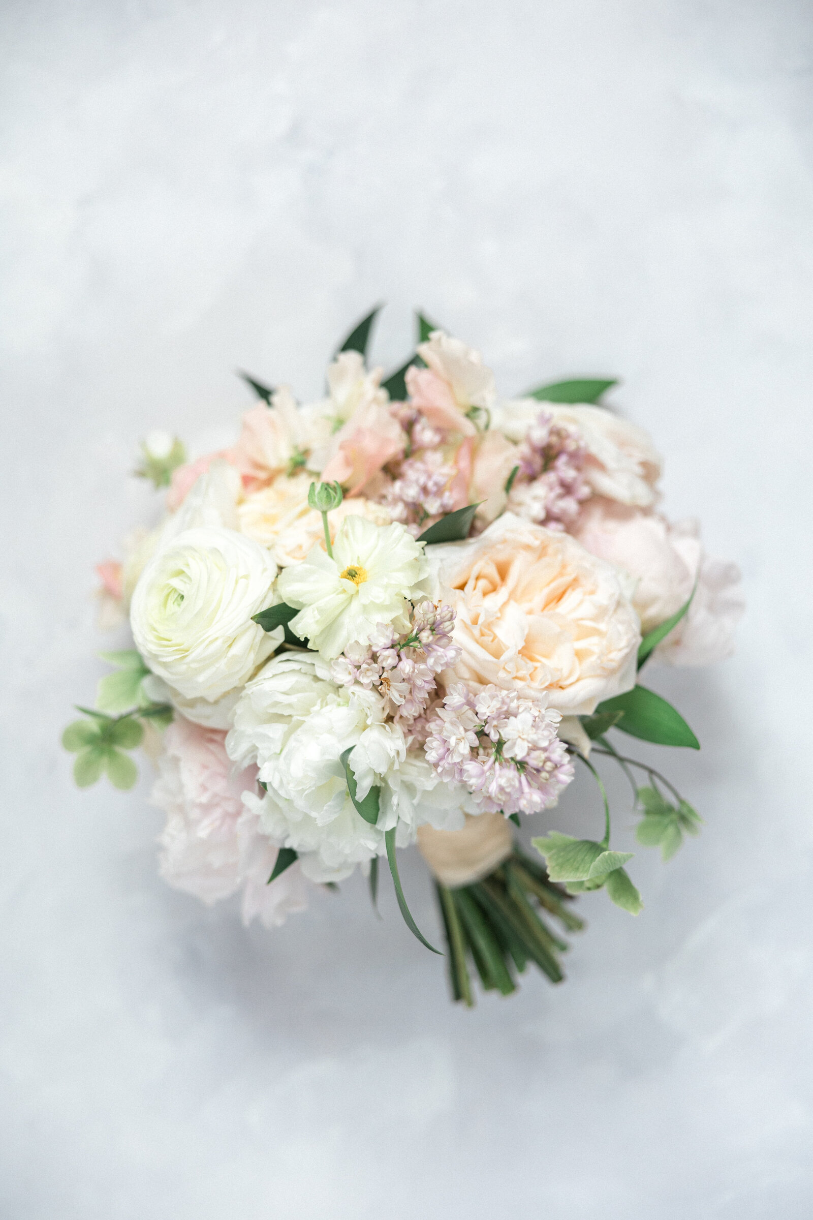 An exquisite spring bouquet  from Stoneblossom Floral and Event Design featuring ranunculus , garden rosaes, and lilac