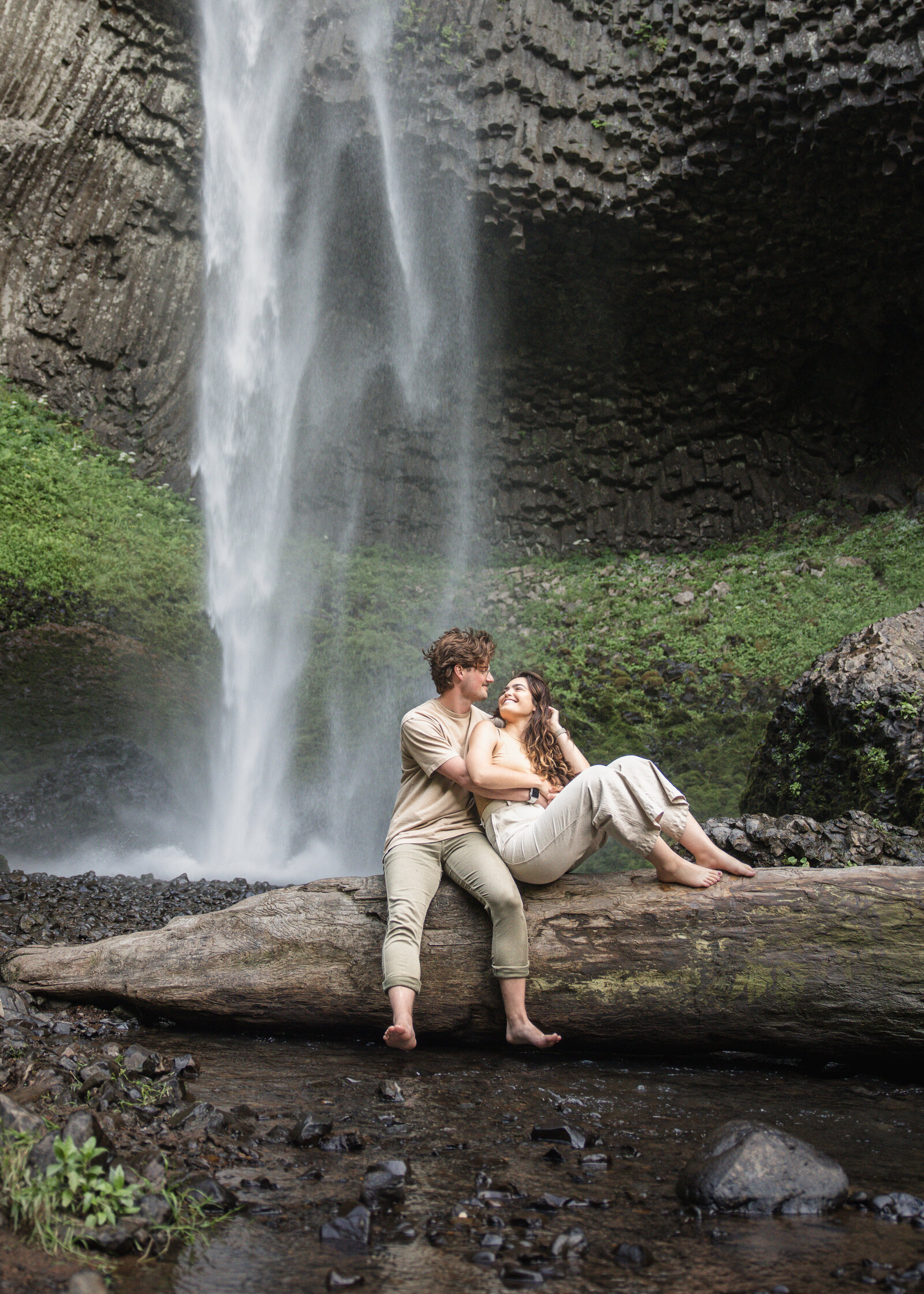 Couple sitting on log in front of latourell falls