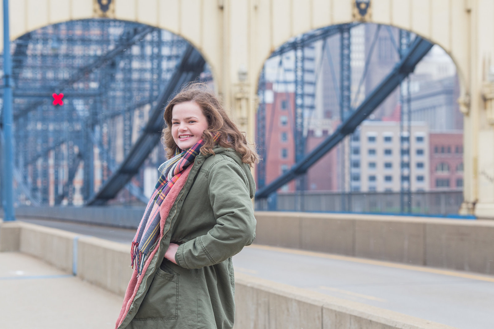 senior girl stands on smilthfield street bridge on a windy winter day in pittsburgh