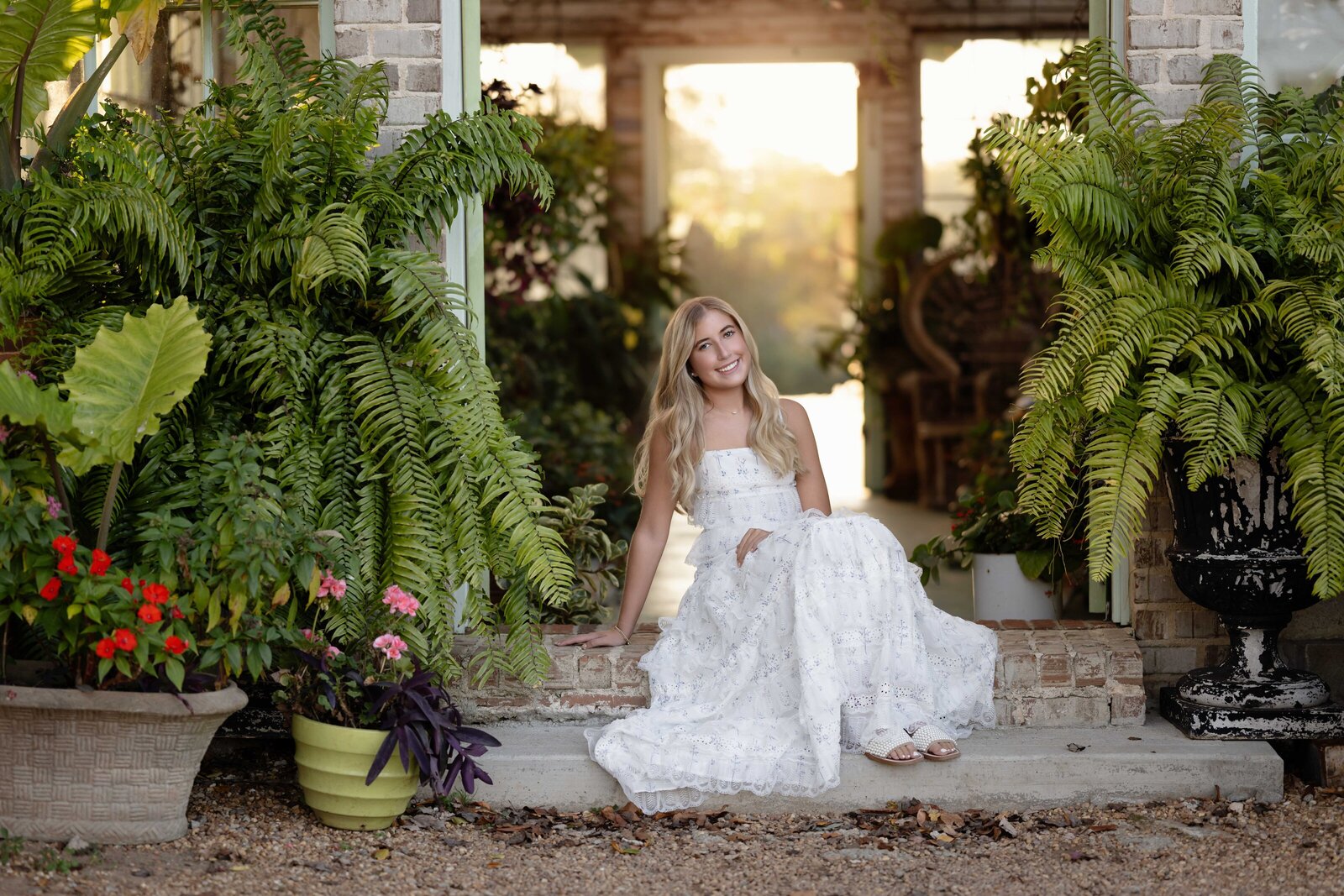 Graduation photo of girl sitting on steps of greenhouse. Senior graduation photos taken by Jenni Nikki Photography in Atlanta, GA