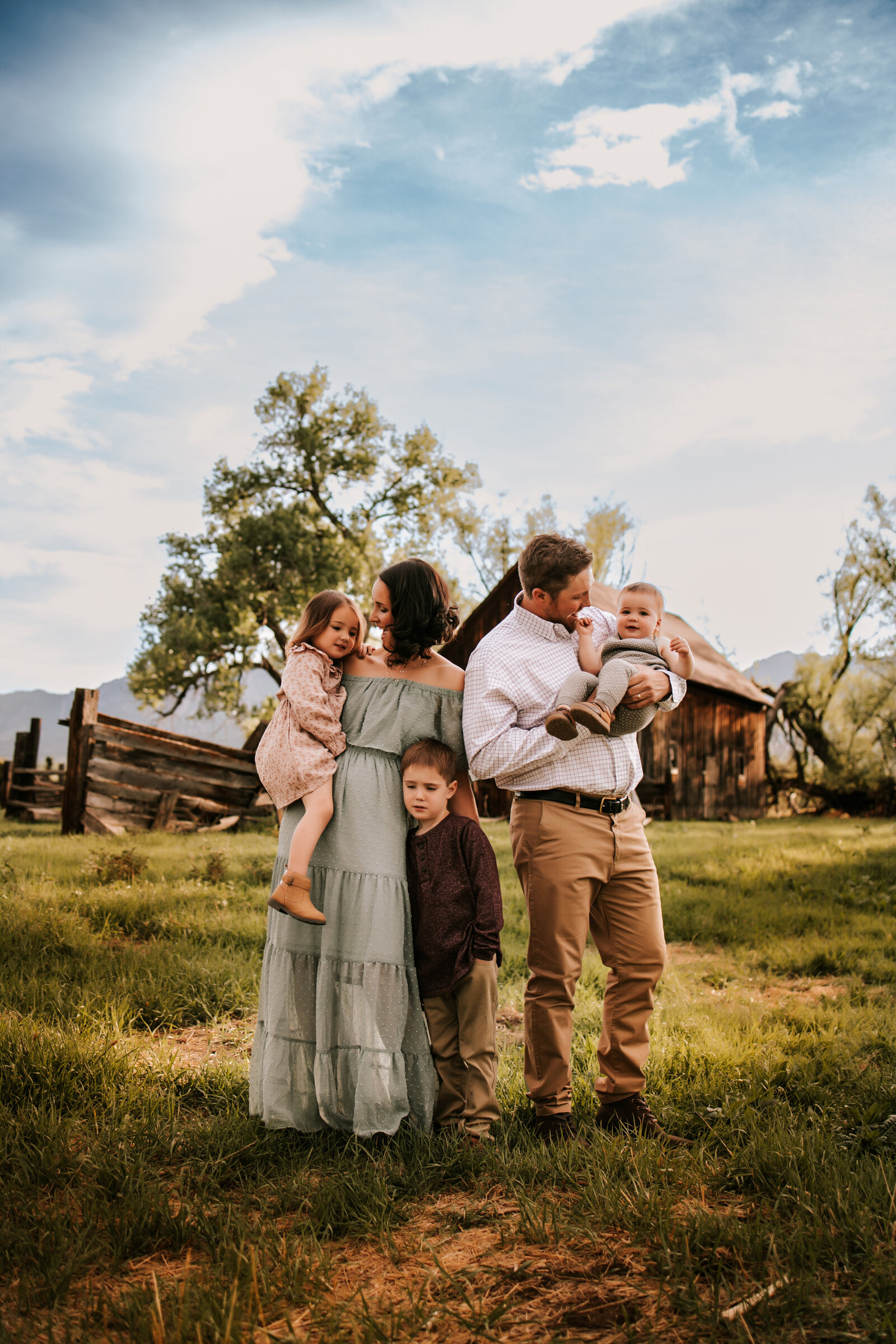 family of five standing in front of a brown bard with blue skies