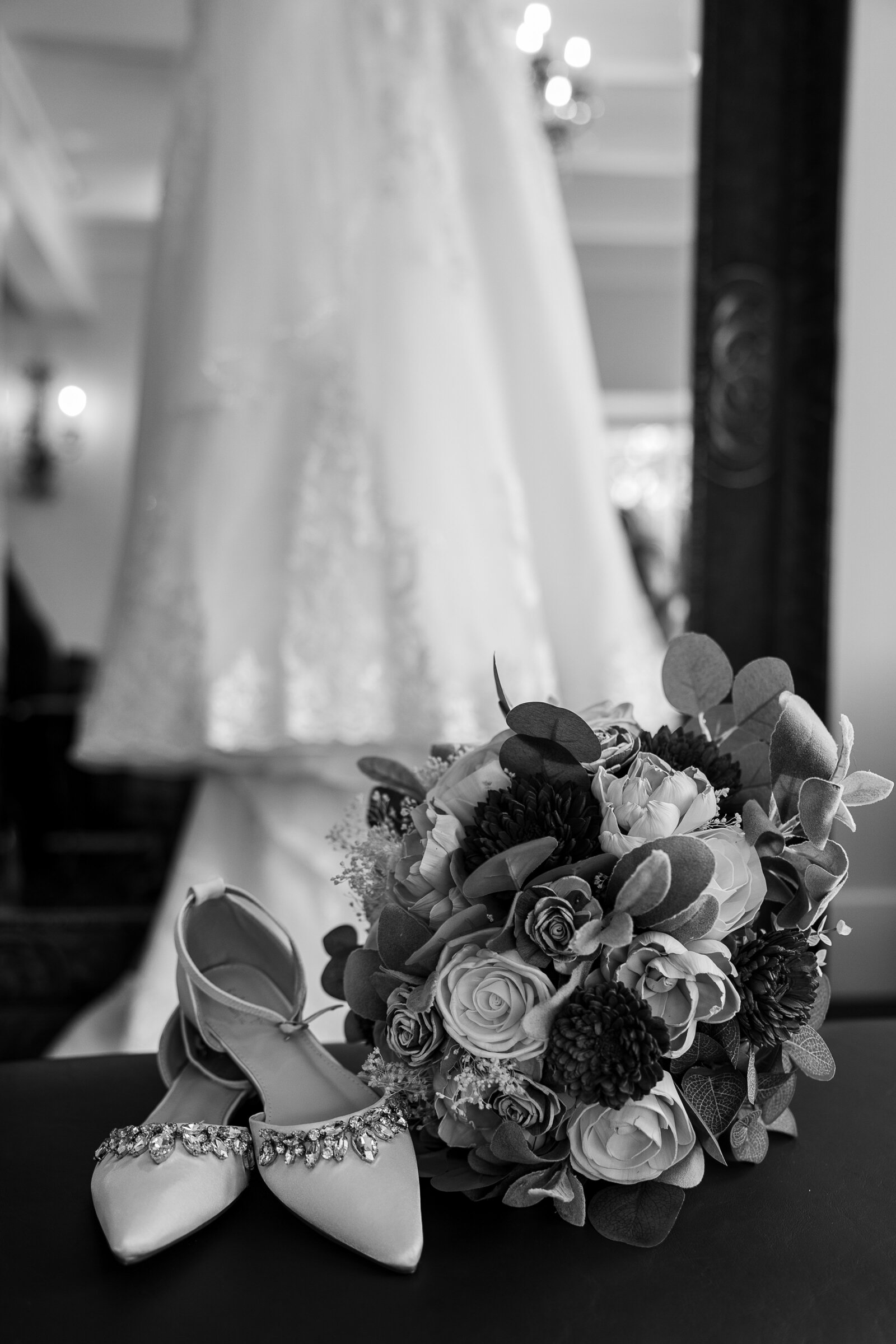Artistic black and white detail of the bride’s gown with bouquet and heels on the floor at Perona Farms.