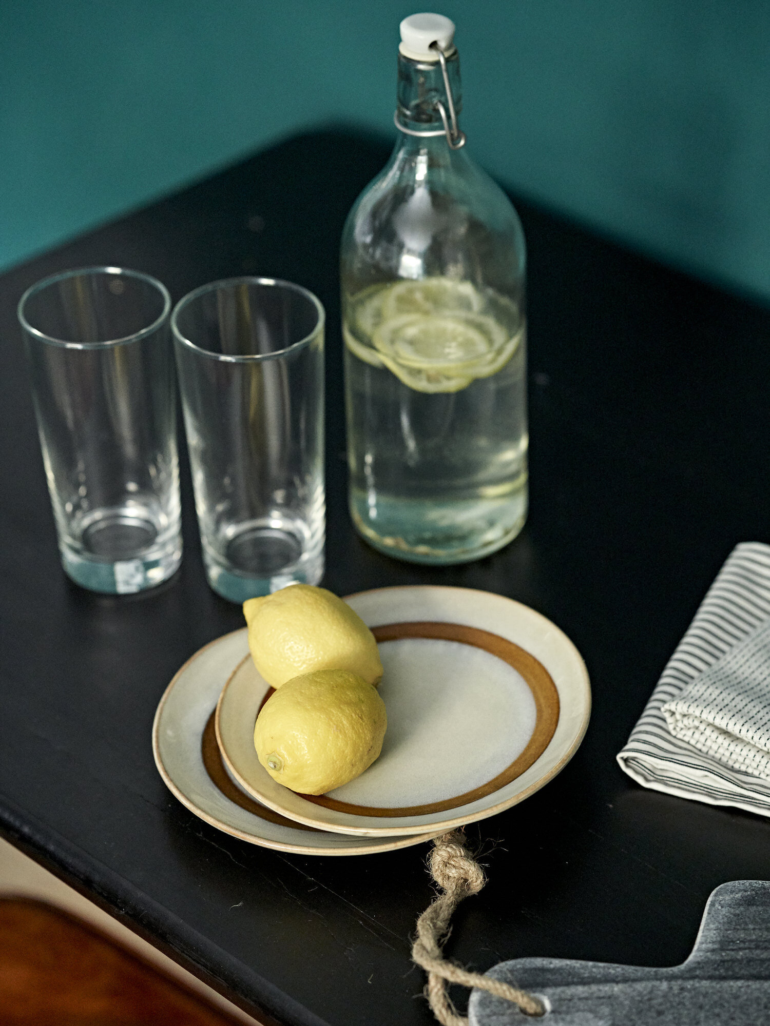Lemons water and plates on black table