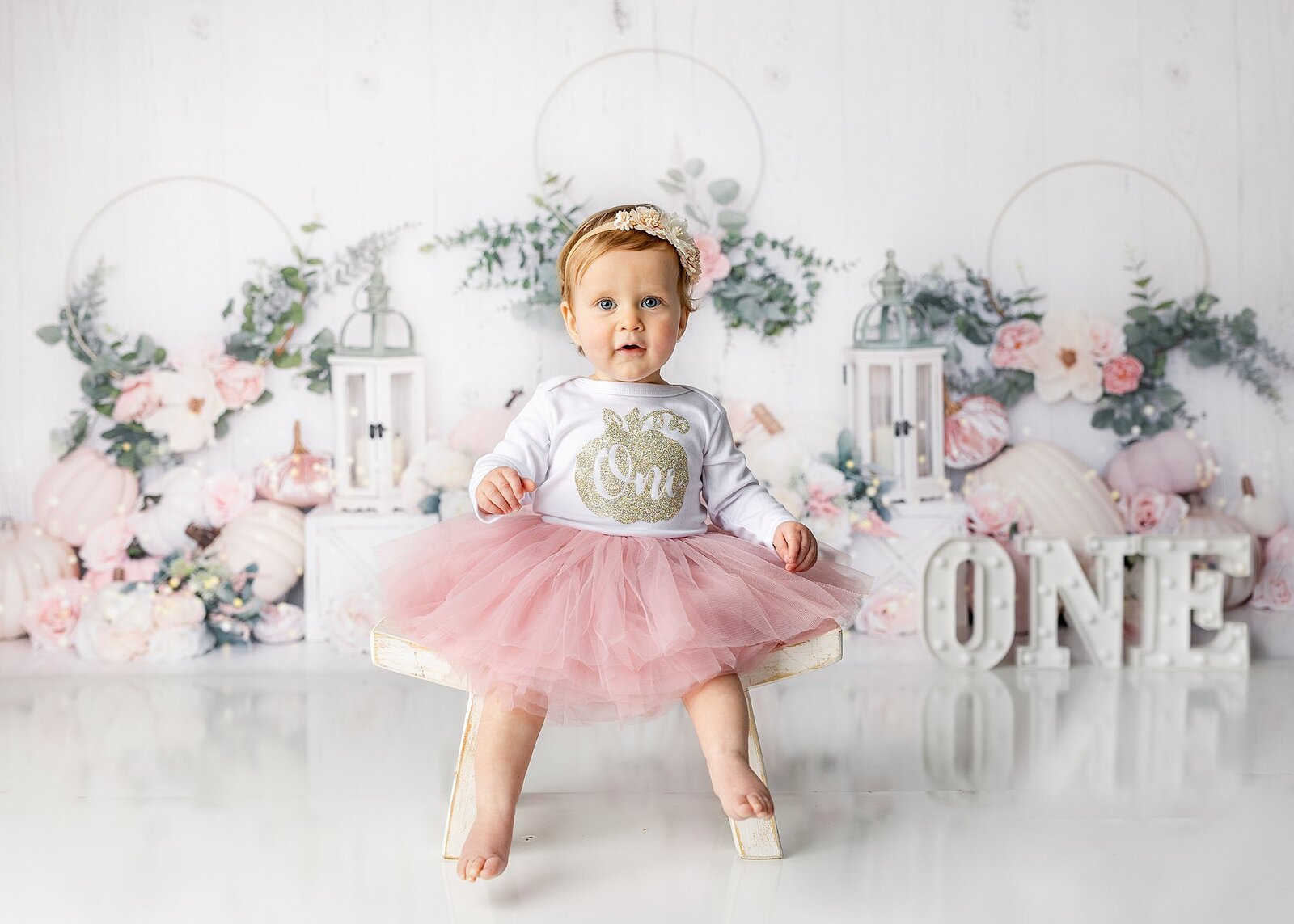 Little girl sitting on a chair  with pink pumpkin backrop