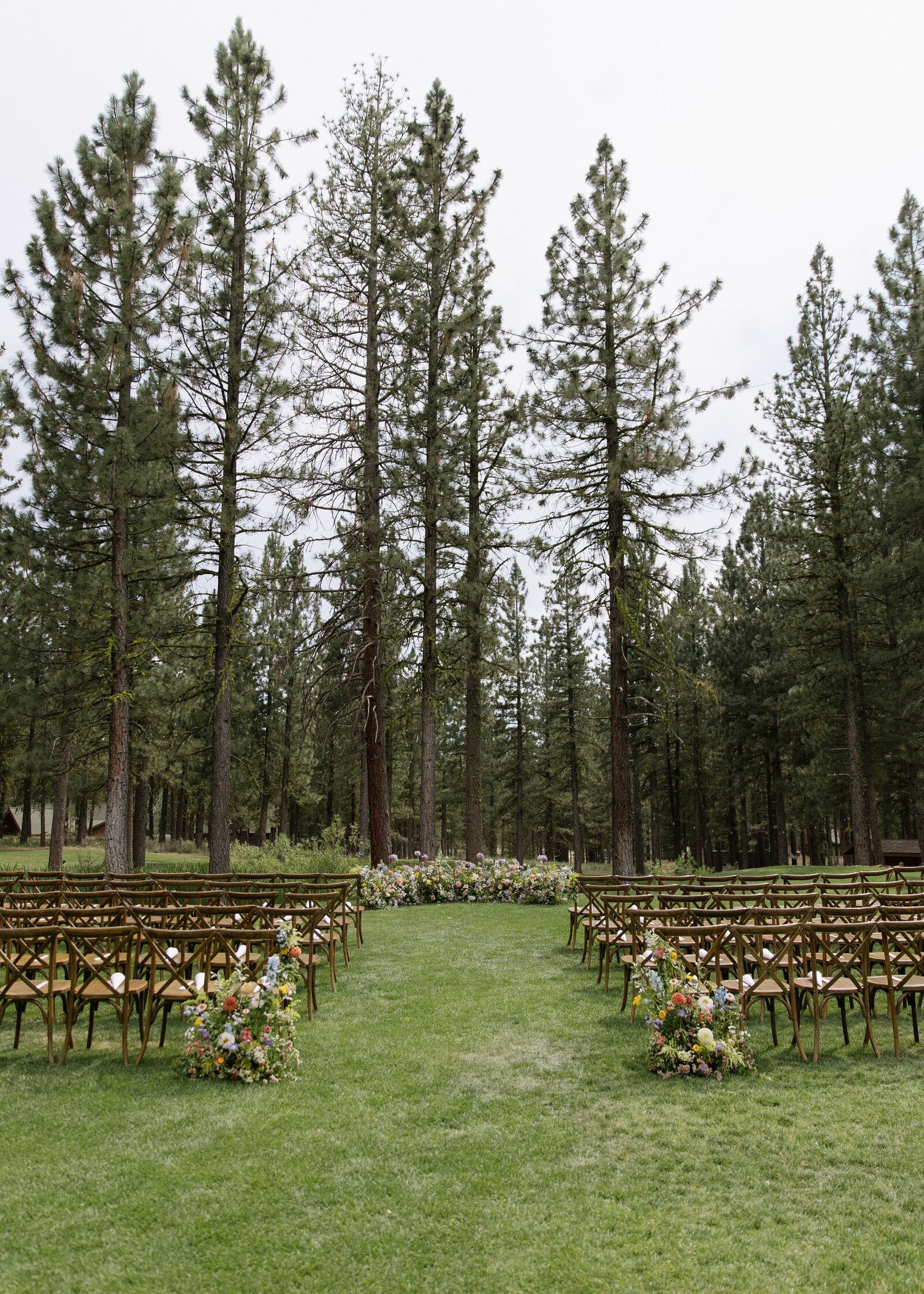 Colorful floral aisle and wooden chairs at Tahoe forest ceremony