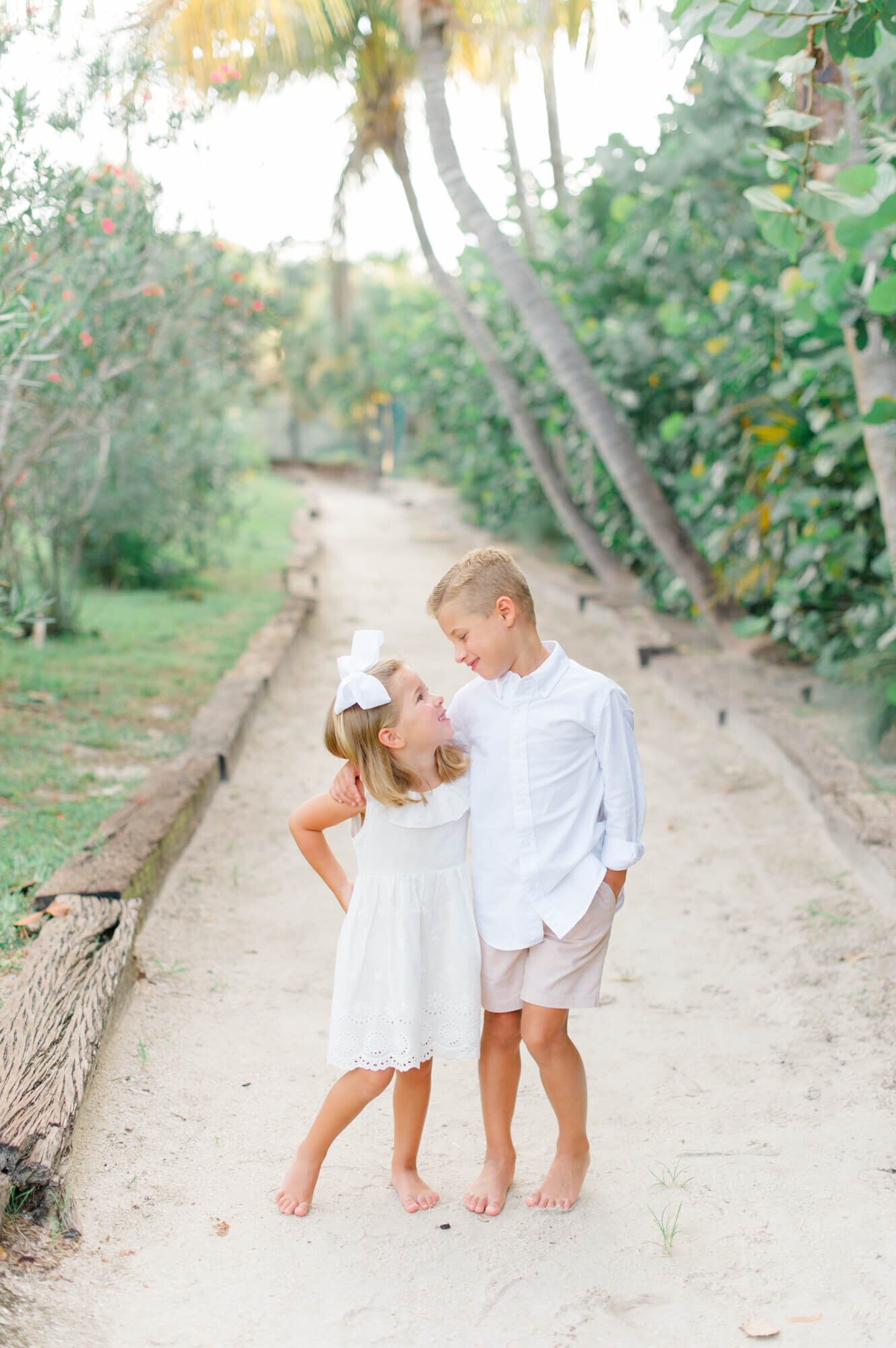 the cutest brother and sister smiling at each other on a beach path in Florida