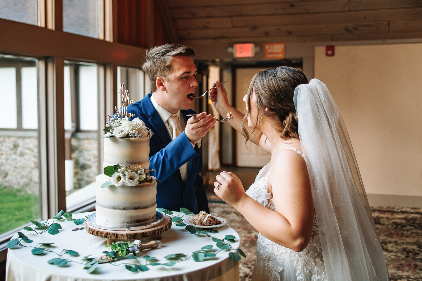 A bride and groom feed each other a piece of their wedding cake at their reception at Peek n' Peak Resort. 