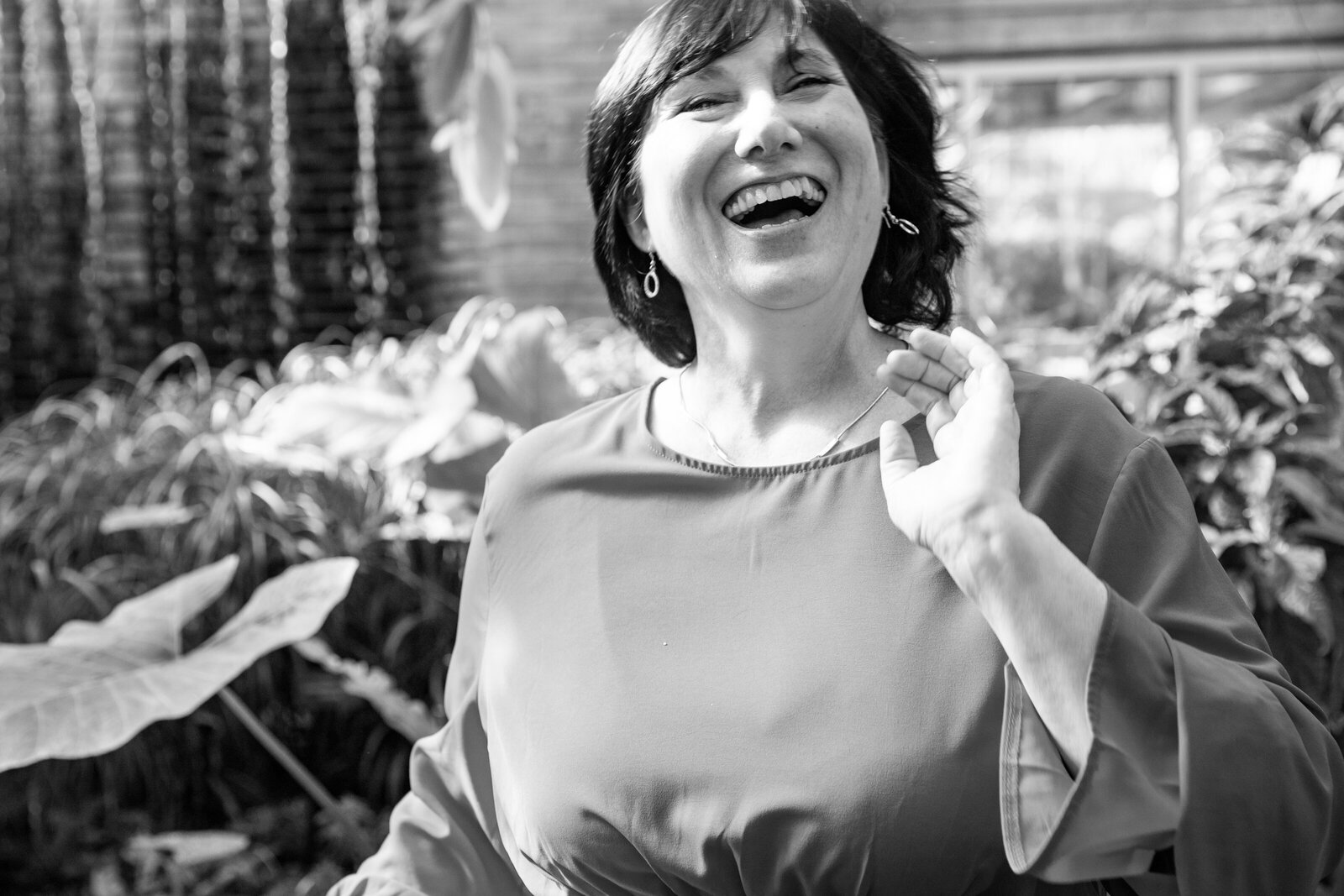 woman laughs at camera as she flips her hair at matthaei botanical gardens conservatory
