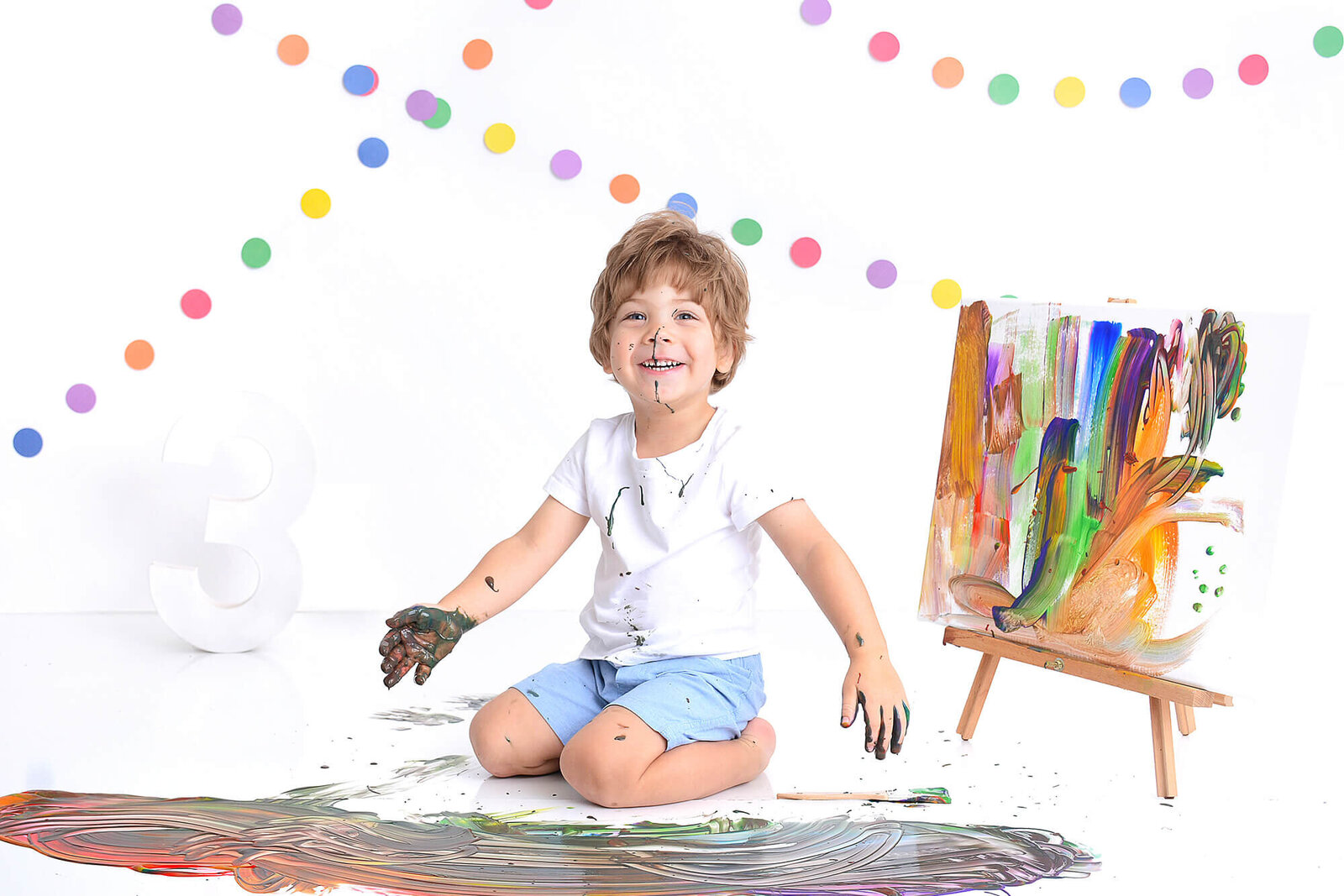 boy smiles at the camera while covered in paint