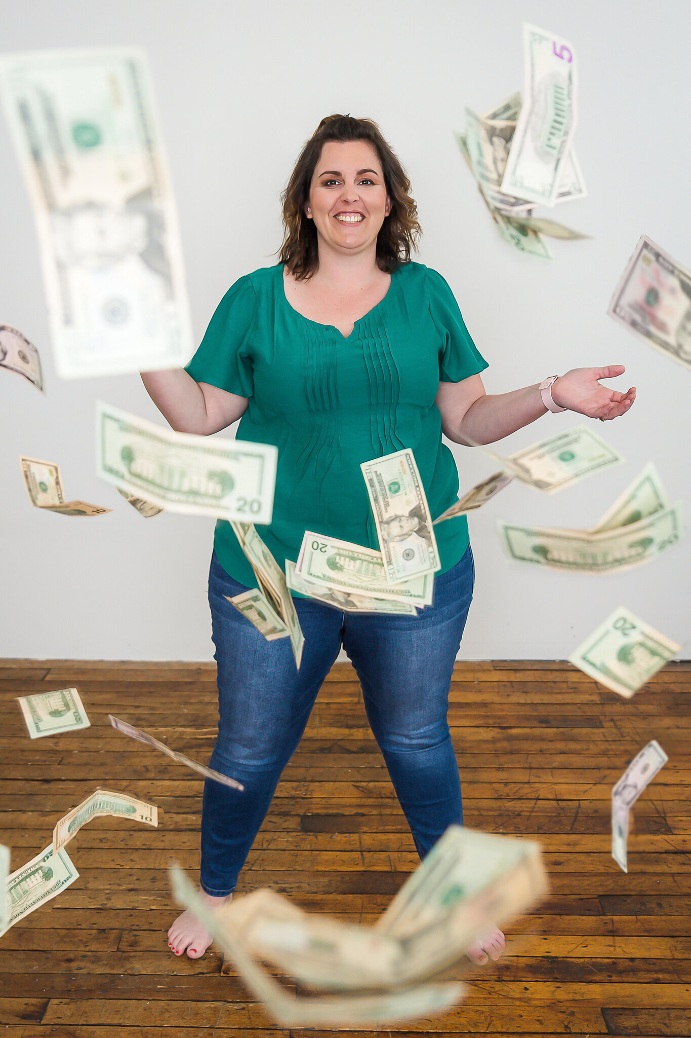 Woman in green shirt and jeans throwing money in the air