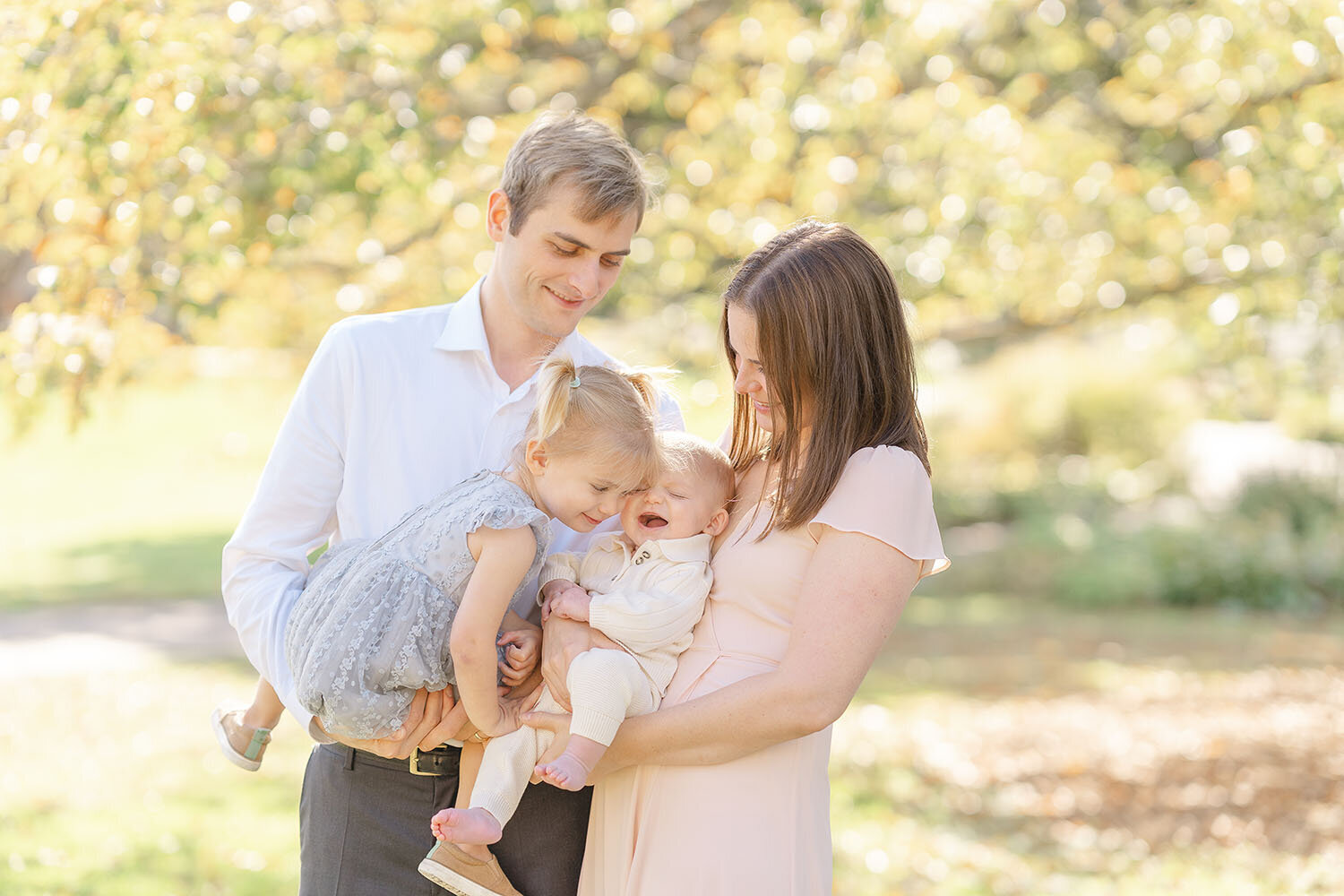 big sister and baby laughing while held by parents in McLean, Virginia