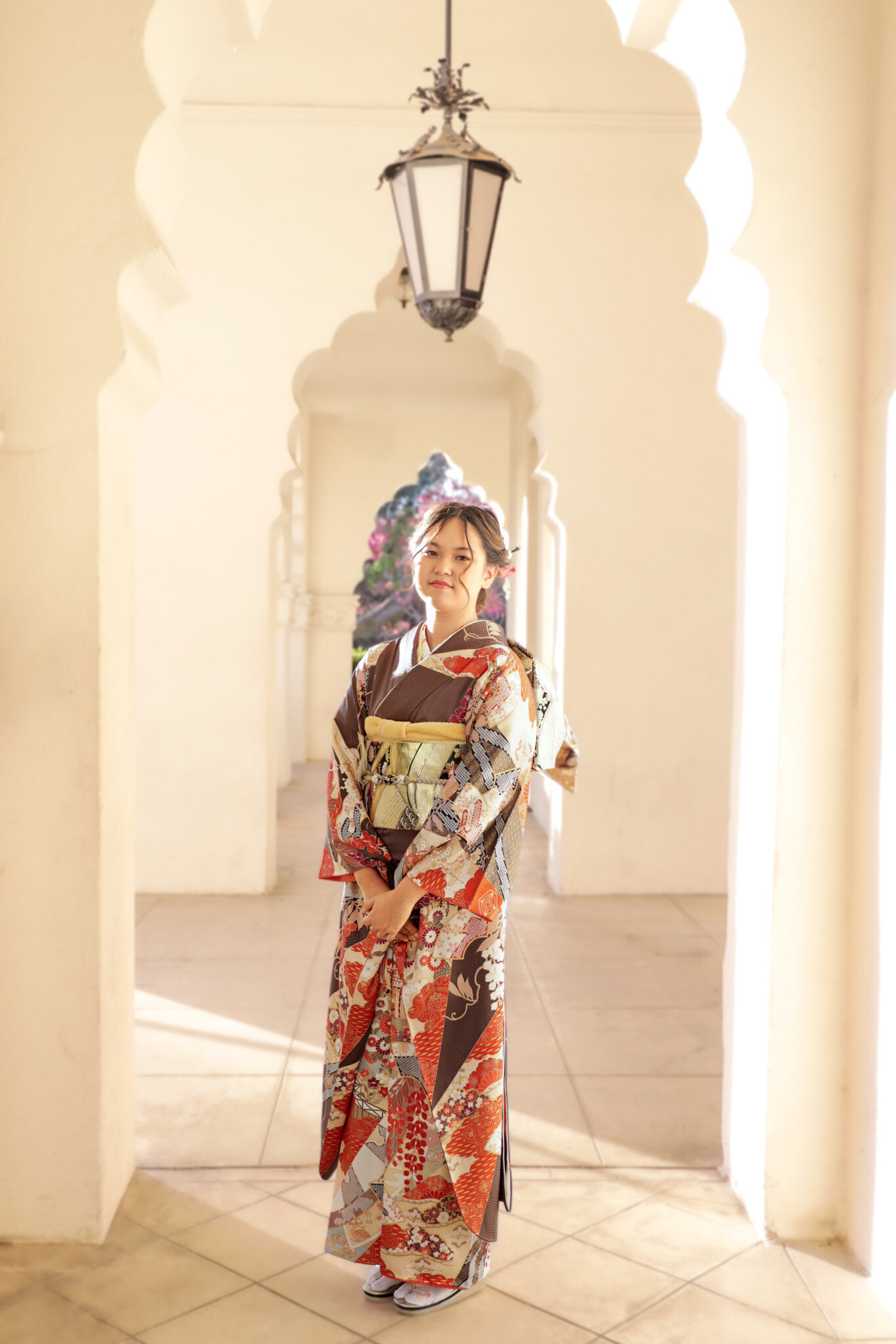 Full-body sunset portrait of a young woman in brown and gold furisode at Brand Park for her Seijinshiki (coming-of-age) photo session. Female kimono rental in Los Angeles | ロサンゼルス・ブランドパークで撮影された夕方の振袖女性の全身ポートレート成人式。女性の着物レンタル