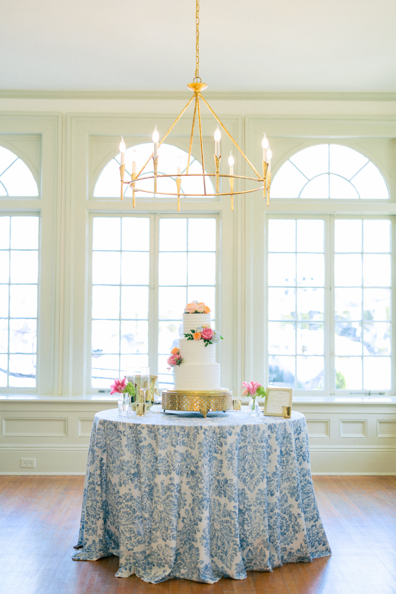 Wedding Cake display on blue and white tablecloth with colorful summer flowers