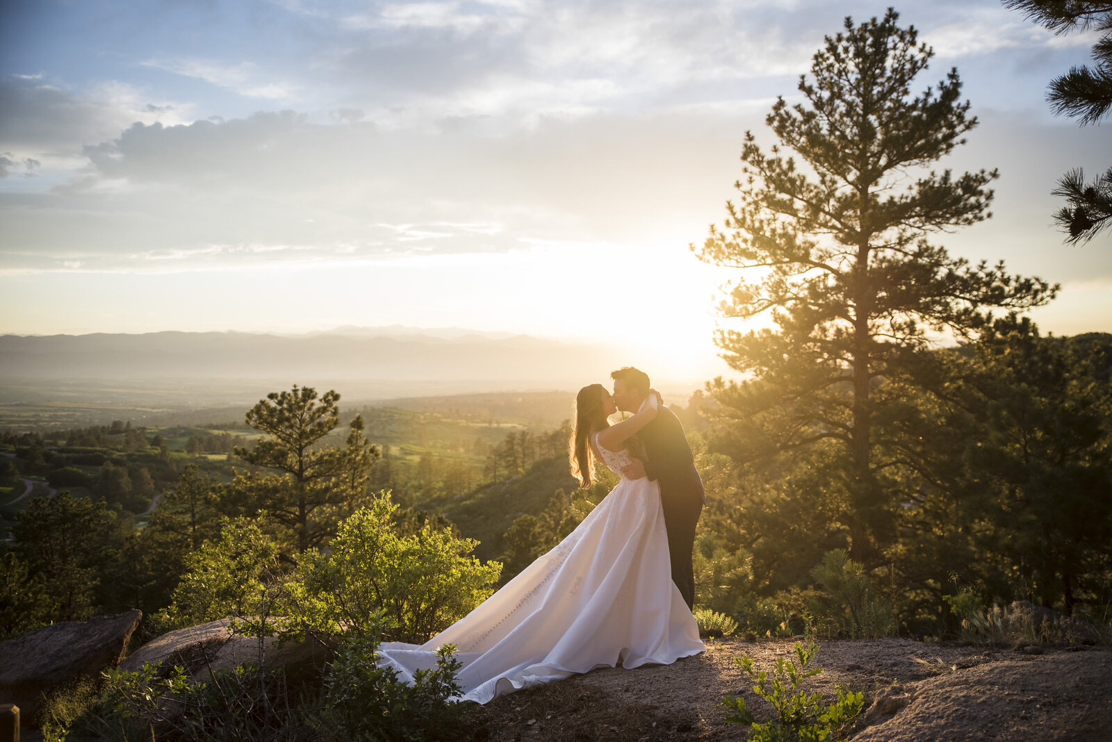 A bride and groom share a kiss at golden hour on Upper Mount Falcon in Morrison, Colorado.