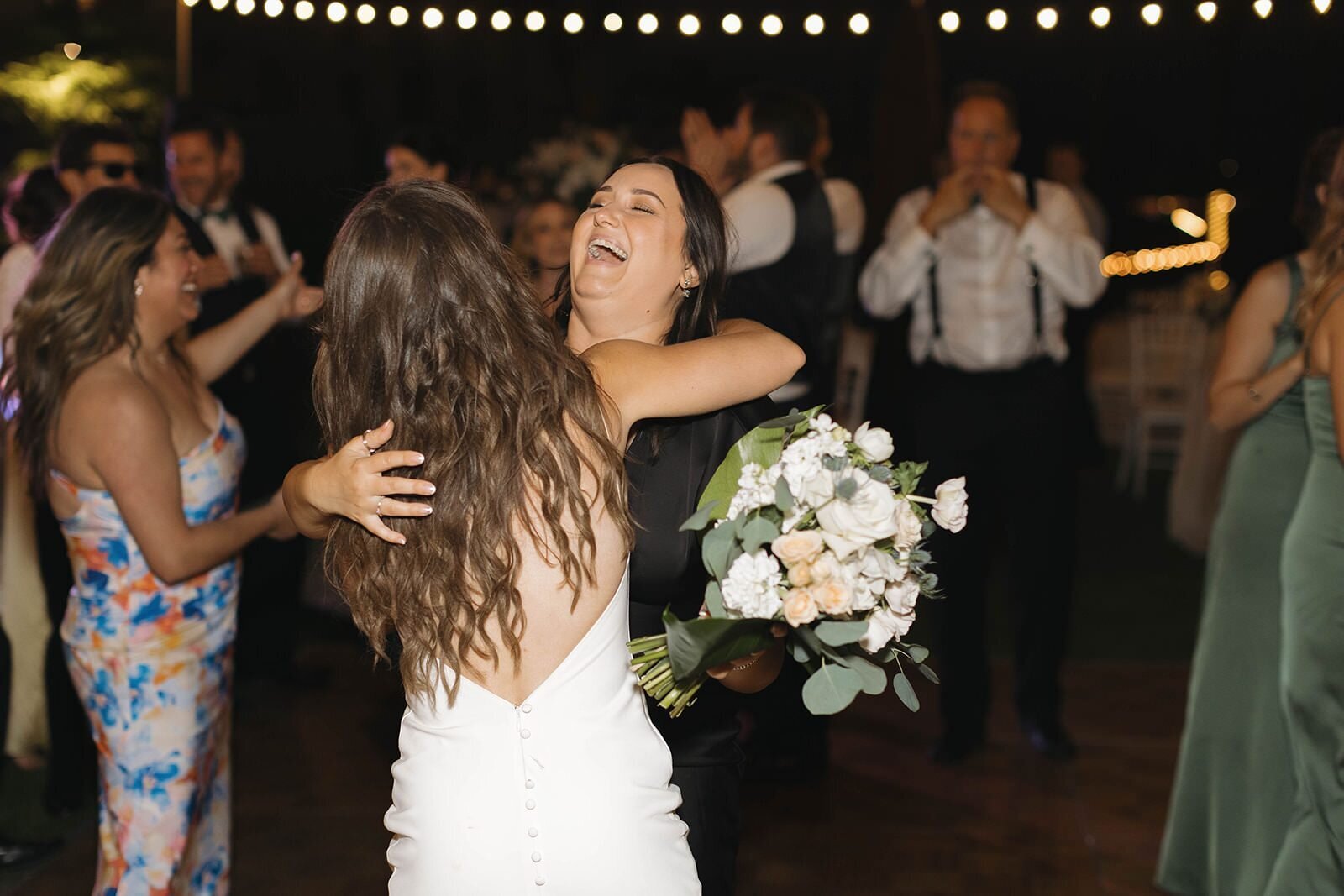 Bride dancing with her bouquet and friends